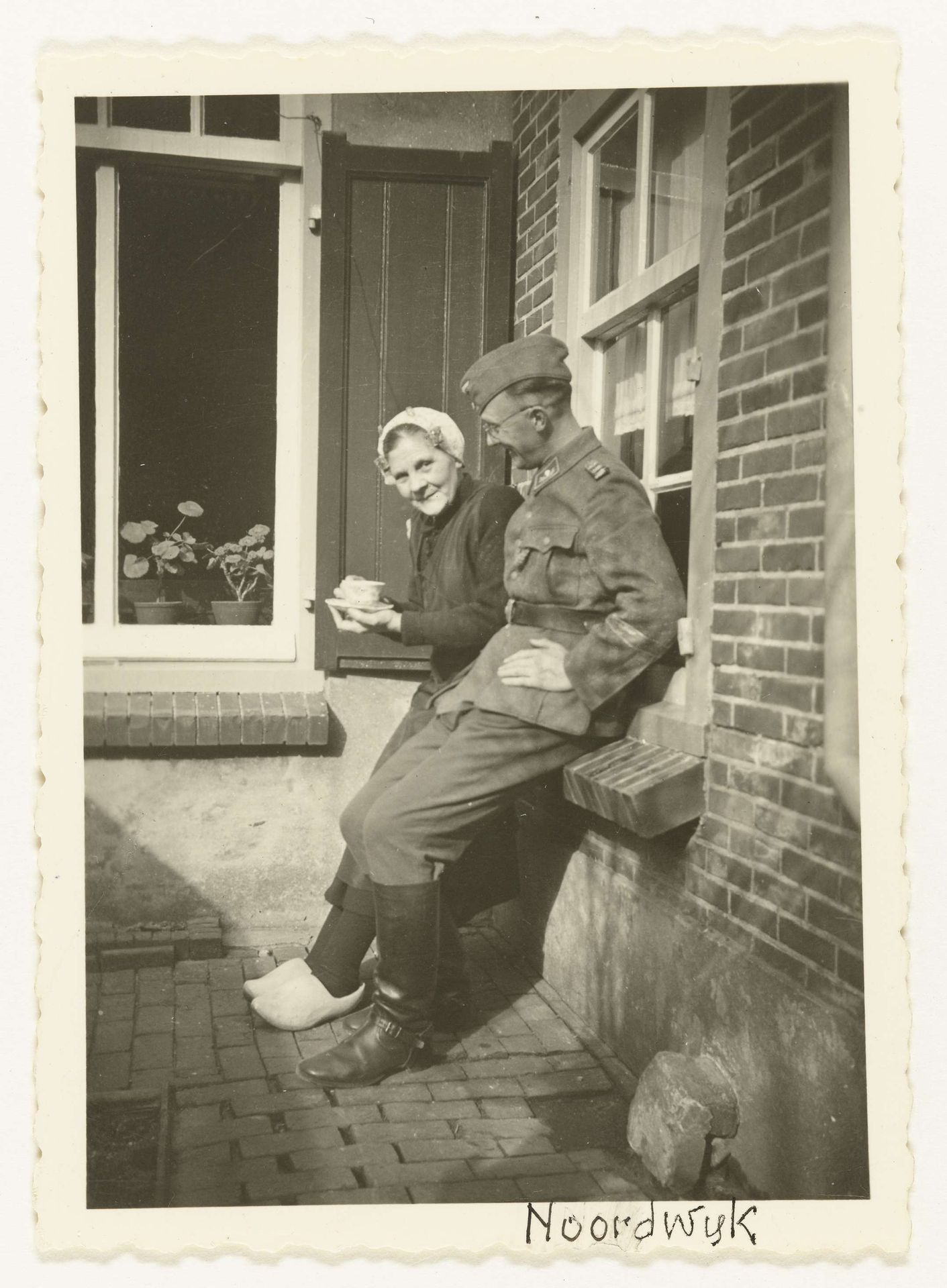 Duitse soldaat met oudere vrouw met kopje koffie by Anonymous