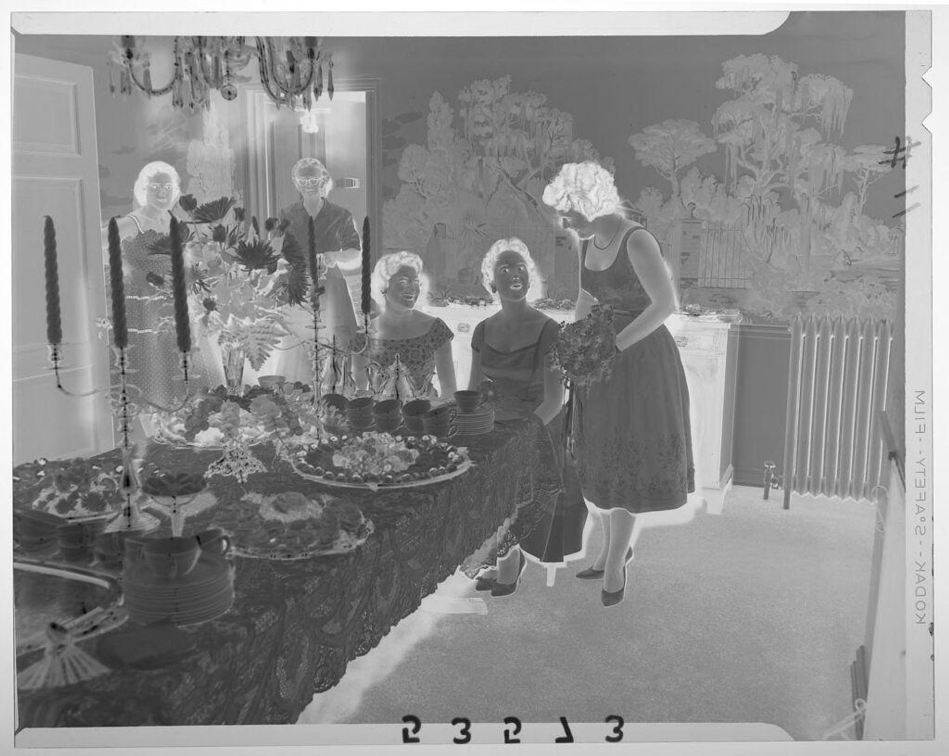 Untitled (three women chatting at large food table in fancy dining room with two others in doorway) by Martin Schweig