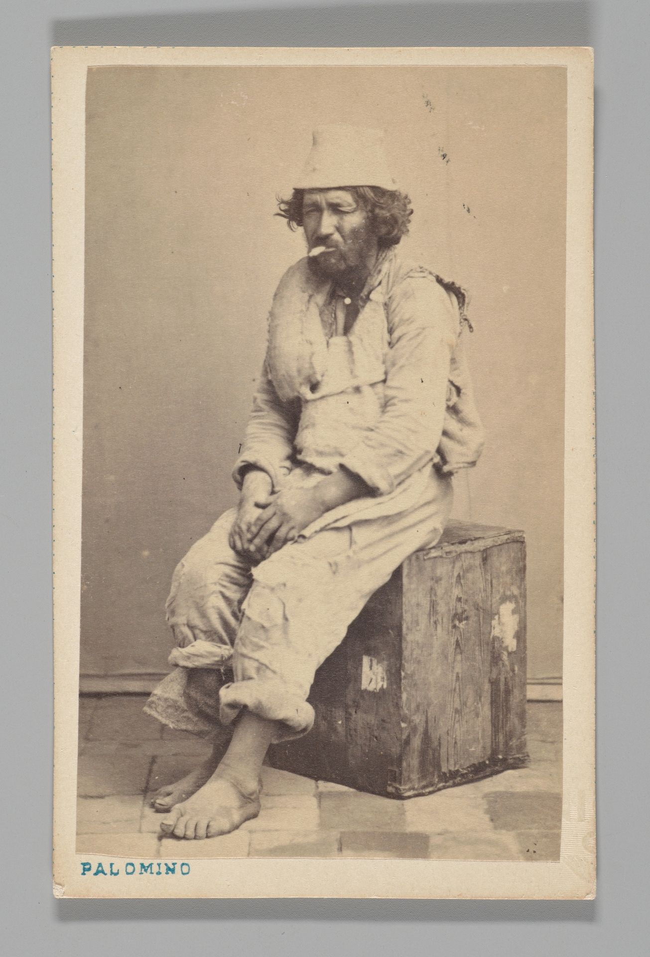 [Studio Portrait: Man Seated on Wooden Box ] by Juan de la Cruz Palomino
