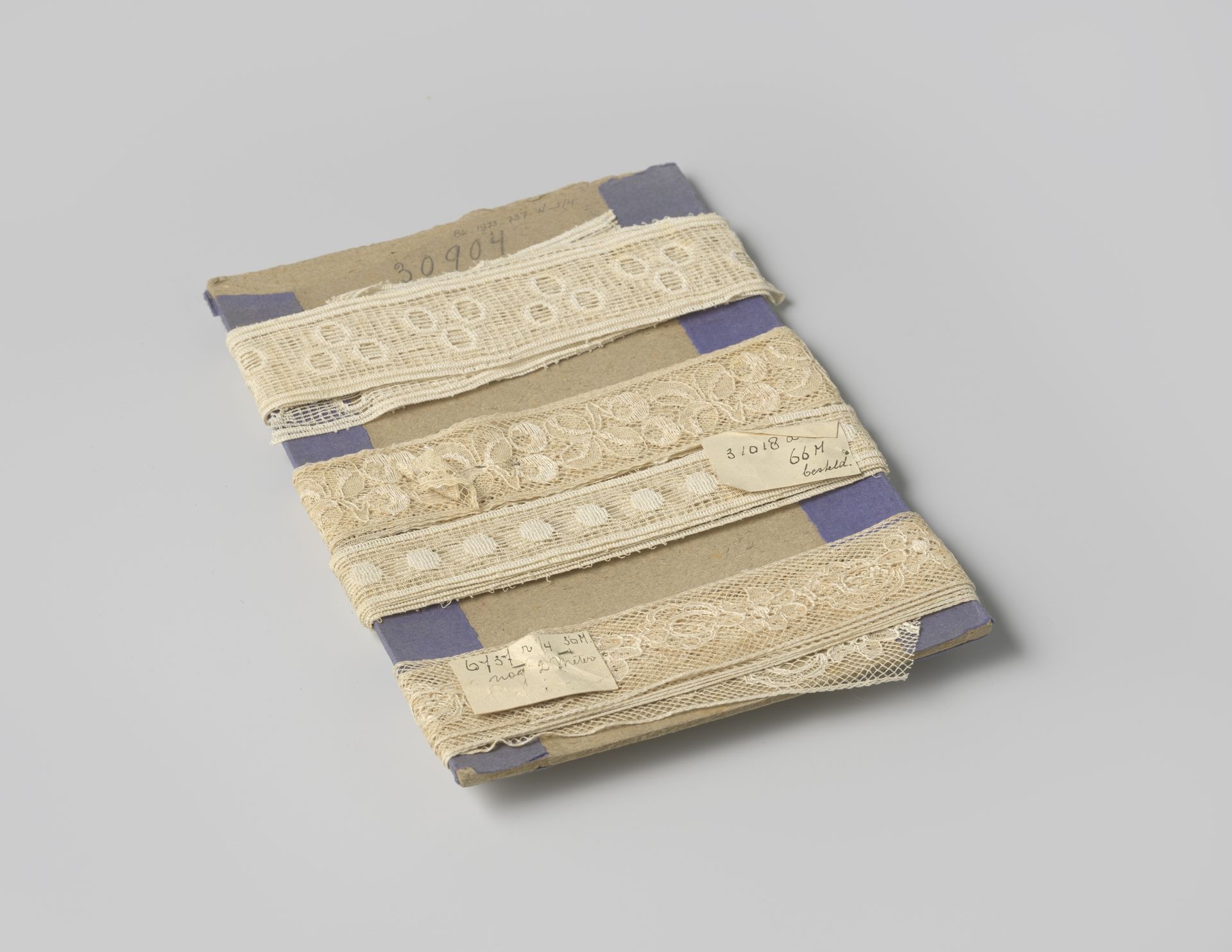 Tussenzetsel van roomwitte machinale kant met patroon van aaneengeschakeld klaverblad, op karton by Gustav Schnitzler