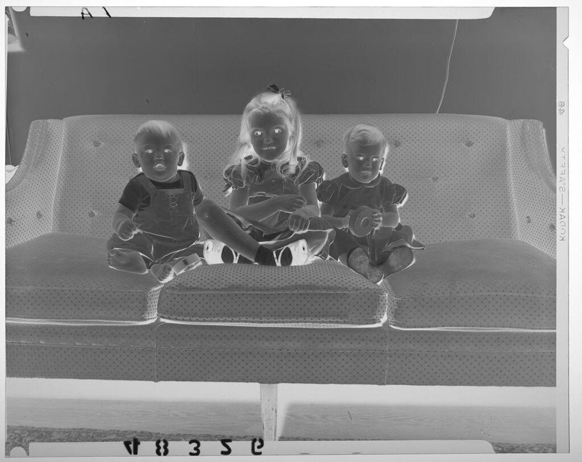 Untitled (young girl posed sitting with two babies on couch) by Martin Schweig