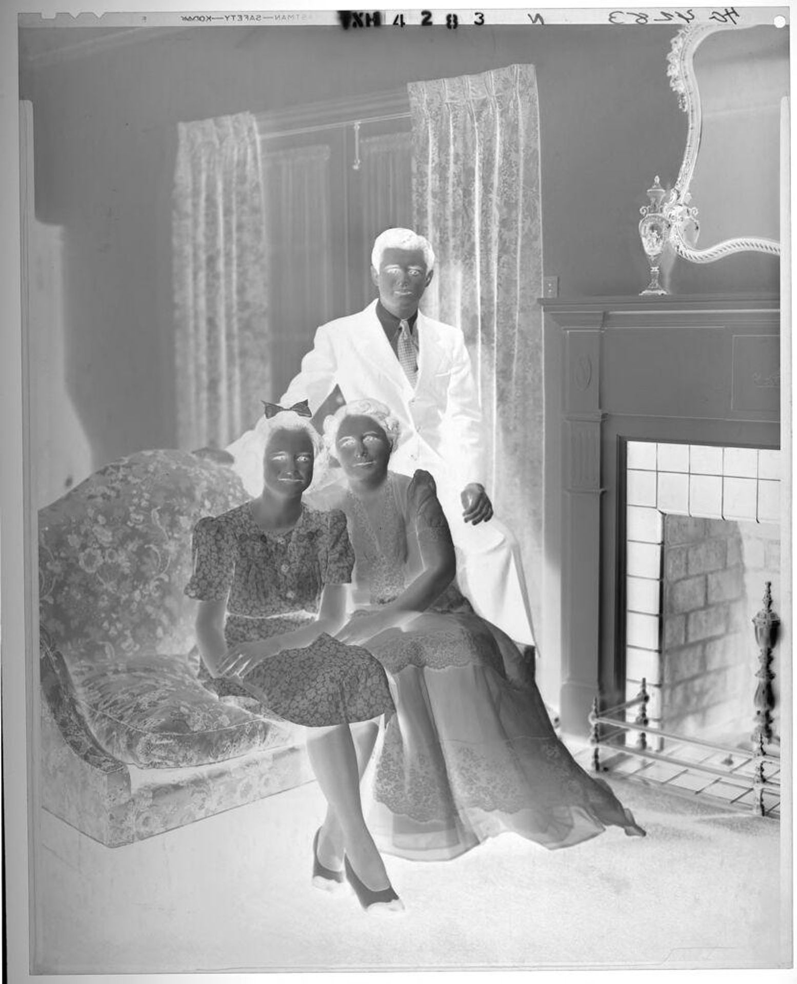 Untitled (mother with son and daughter seated on sofa by fireplace) by Paul Gittings