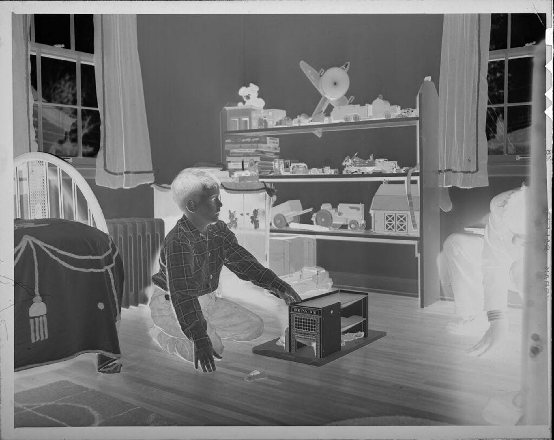 Untitled (boy playing with model garage) by Lucian and Mary Brown