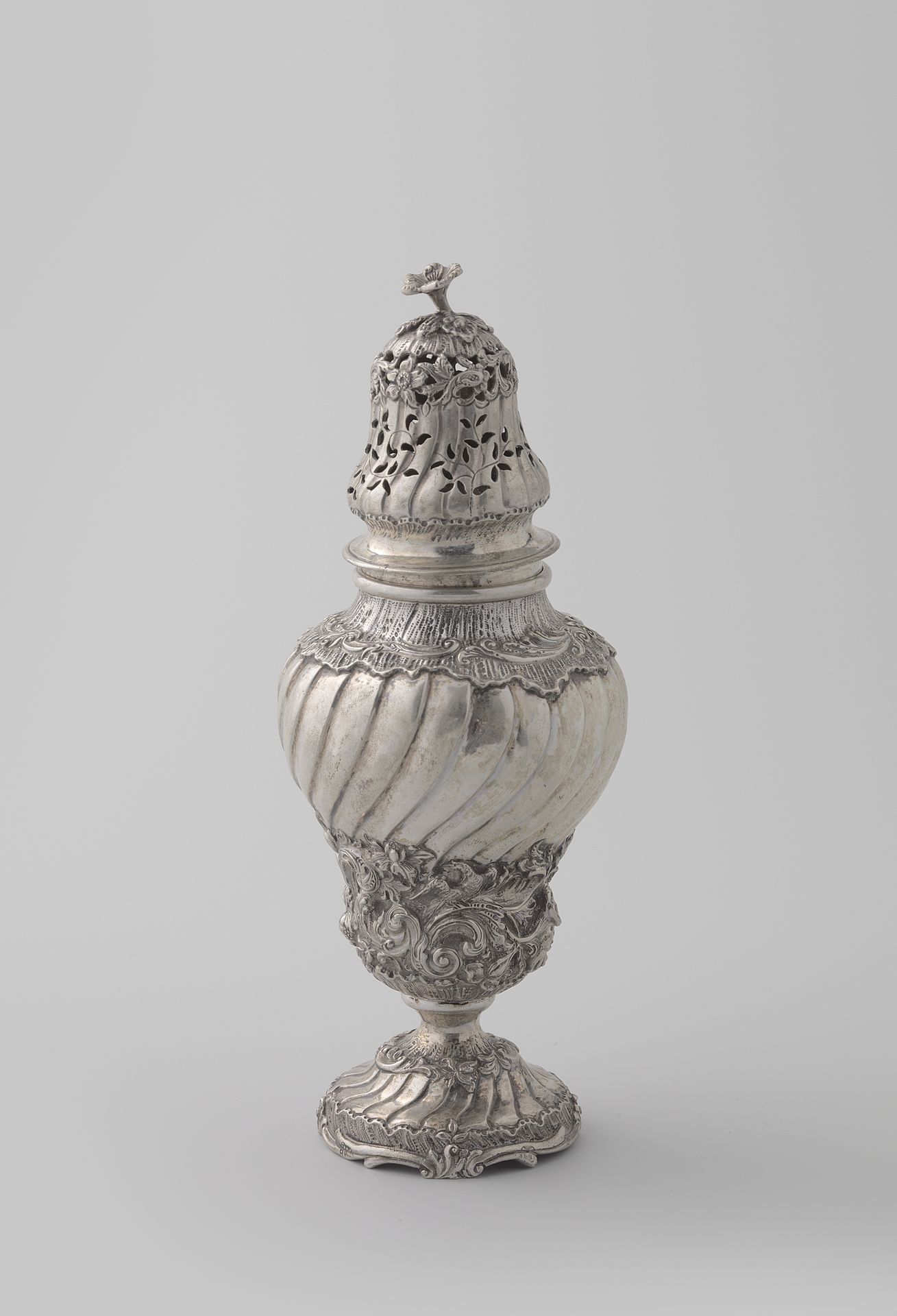 Suikerstrooier van zilver, omgekeerde peervorm op gewelfde voet met getordeerde opengewerkte dop versierd met gedreven rocailles, ranken, bloemen en vogels. by Jan Verdoes