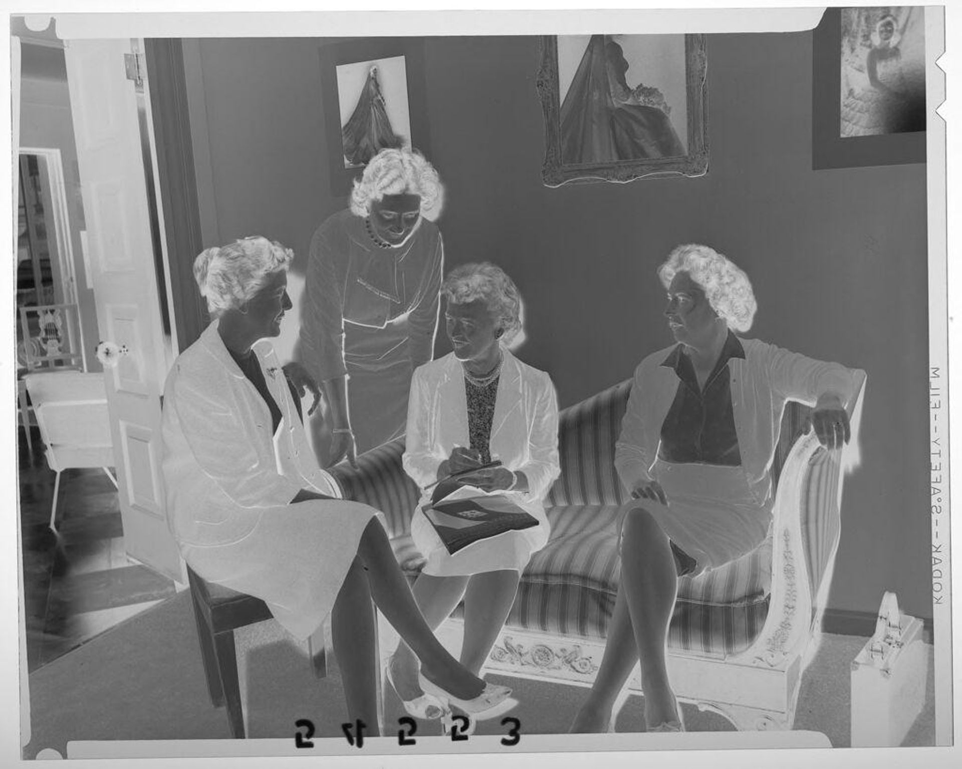 Untitled (four women chatting in room with bride portraits on wall) by Martin Schweig