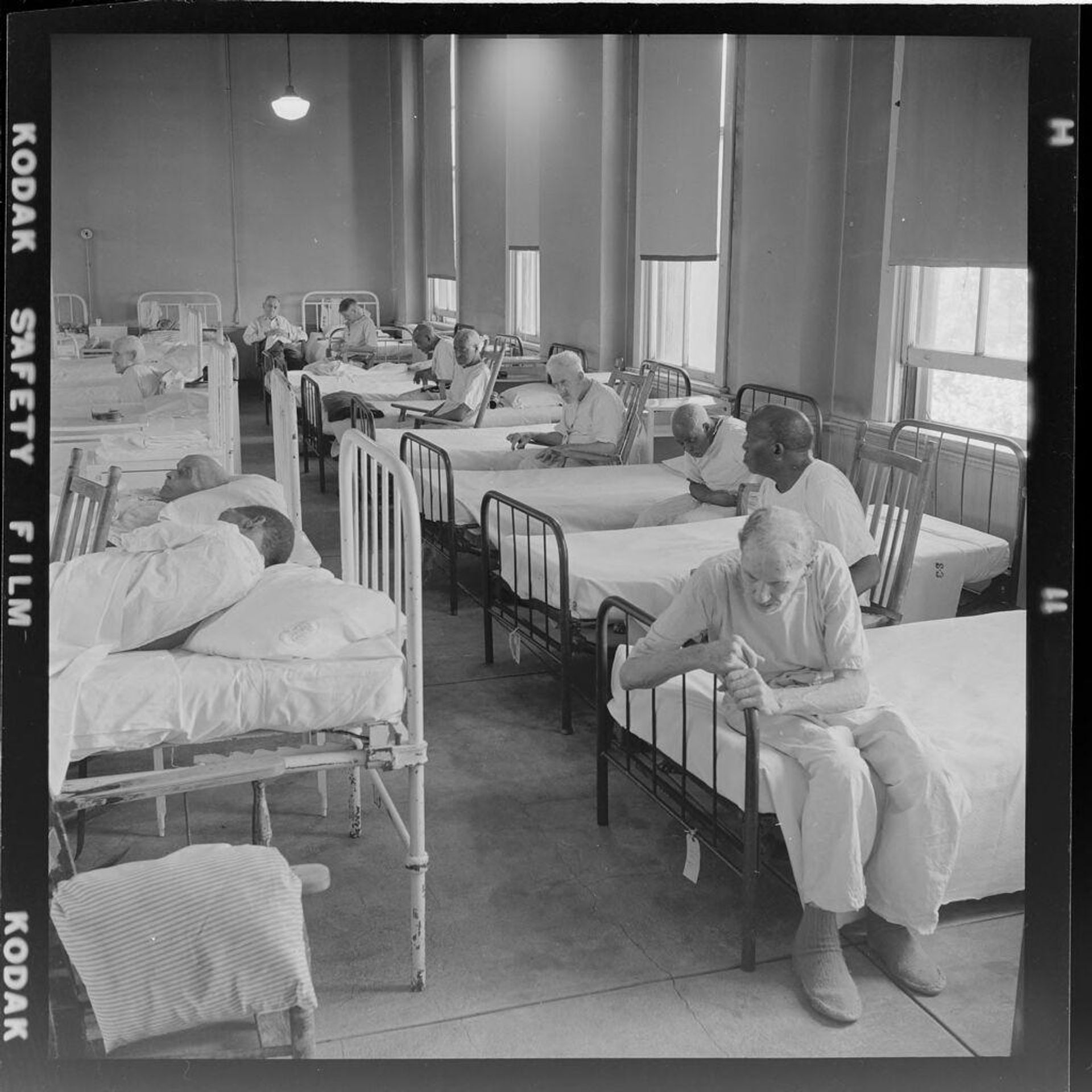 Untitled (people on beds in large room) by Jack Gould