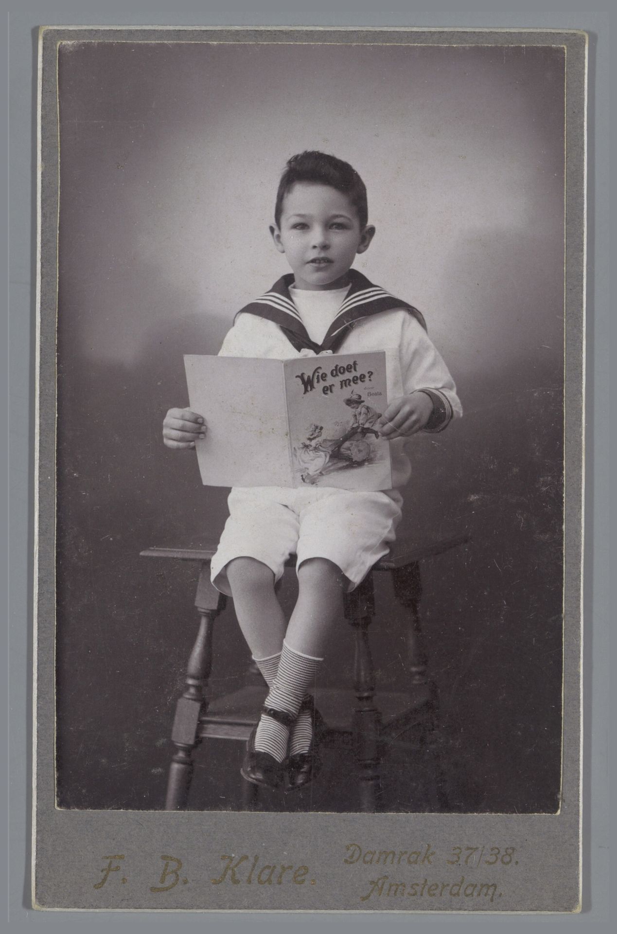 Portret van een onbekende jongen in matrozenpak met kinderboek by F.B. Klare