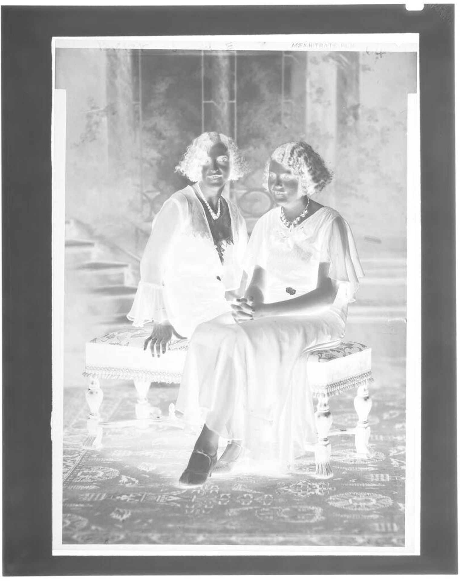 Untitled (two women sitting for portrait on bench in studio) by John Deusing