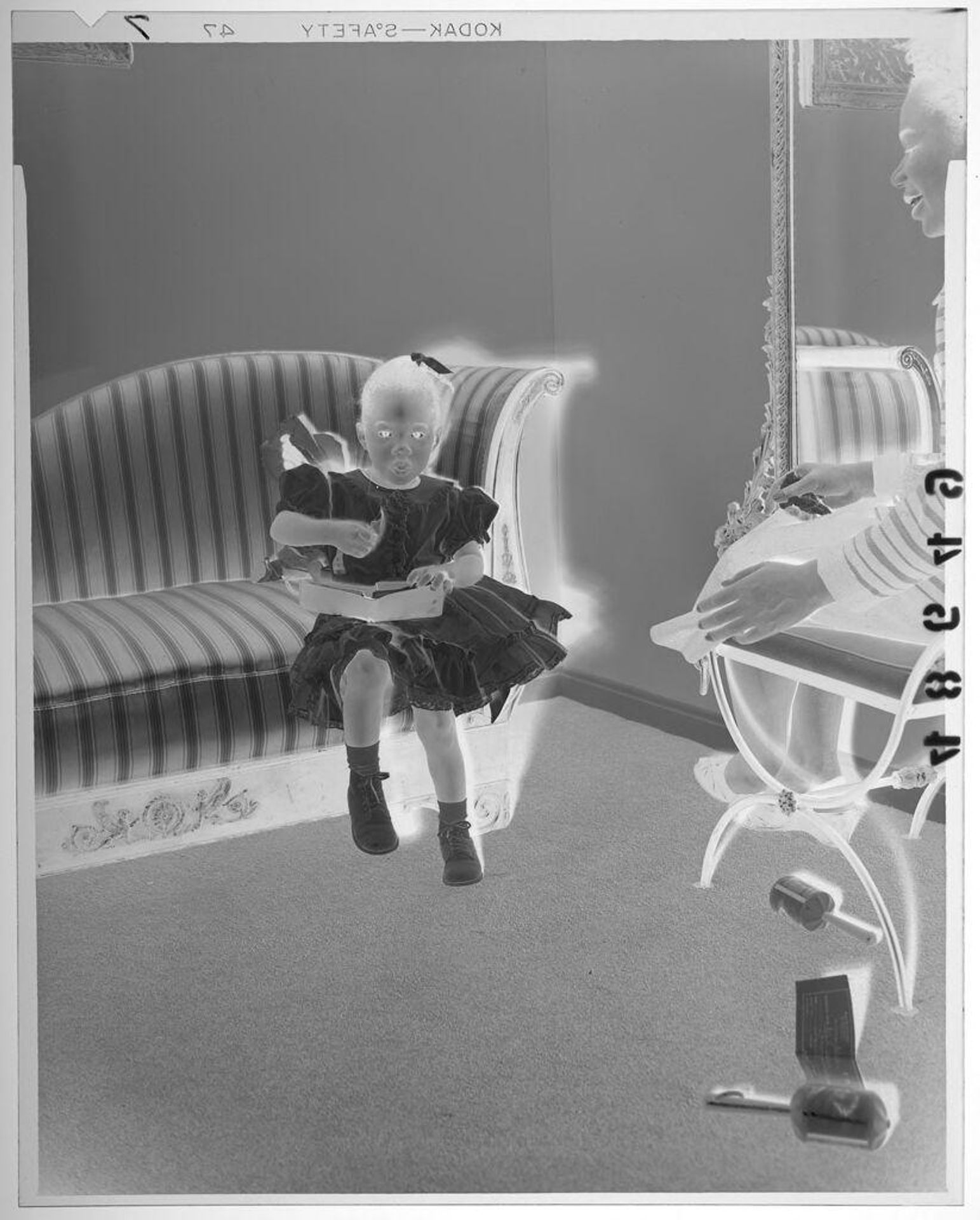 Untitled (young girl in a fancy dress, posed sitting with wallet on couch as mother watches) by Martin Schweig