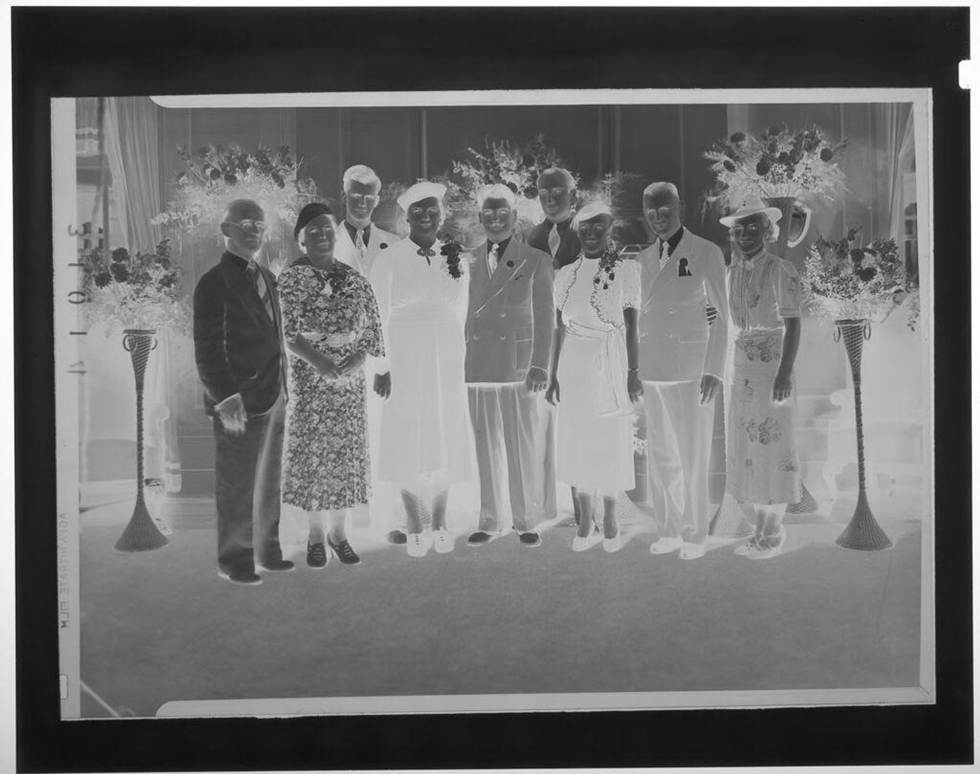 Untitled (group portrait of eight people in formal wear posing in reception room with flowers) by Martin Schweig