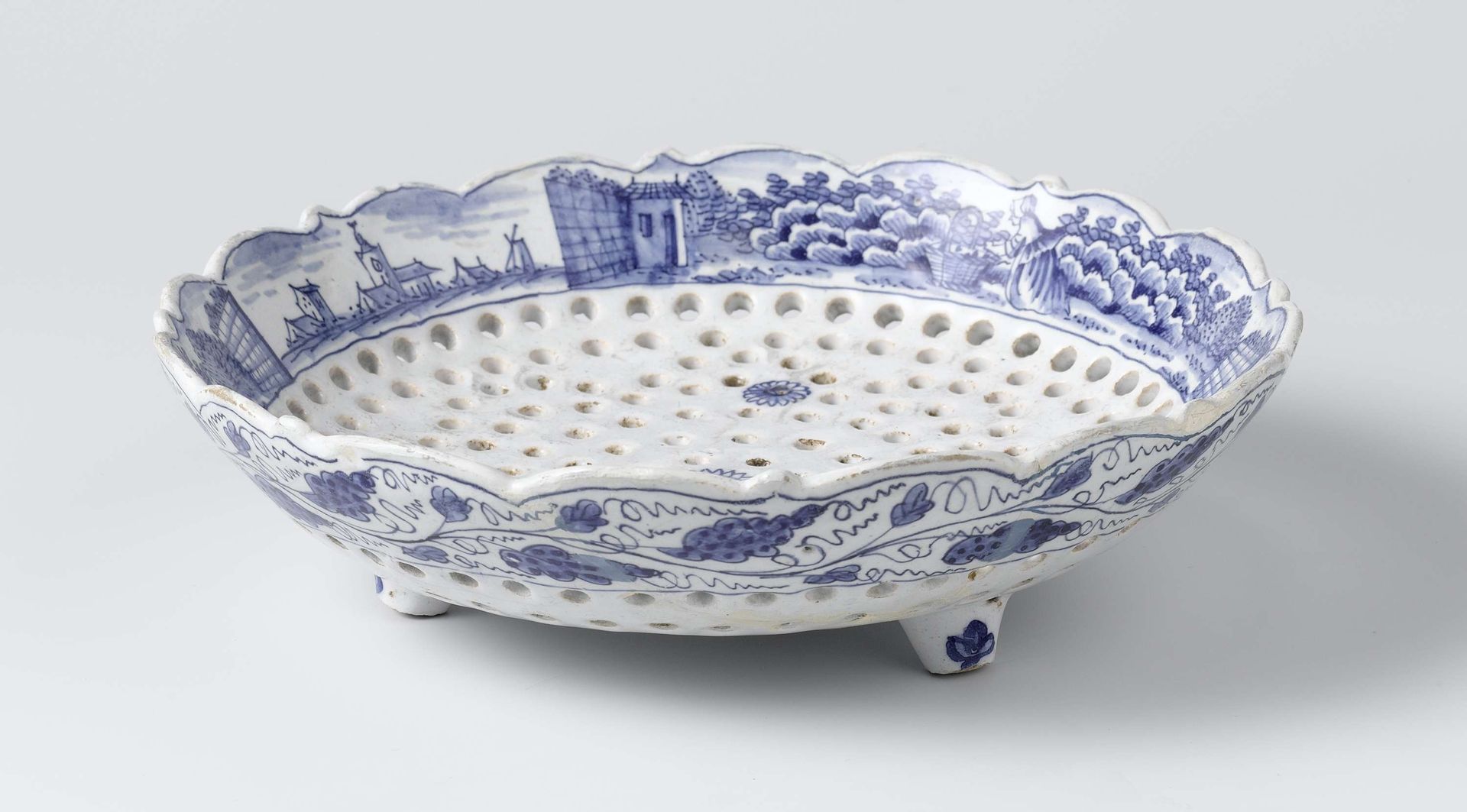 Natfruitschaal van blauw beschilderde faience, met gaatjes in een bloemvorm by De Porceleyne Byl