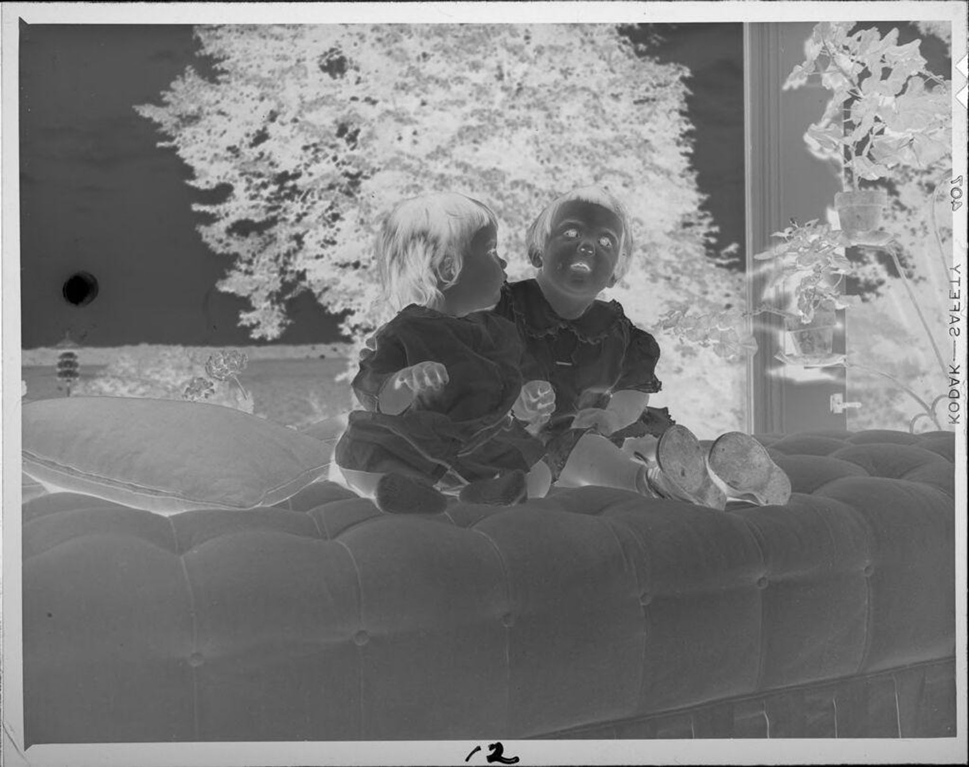 Untitled (two girls on couch in front of window) by Lucian and Mary Brown