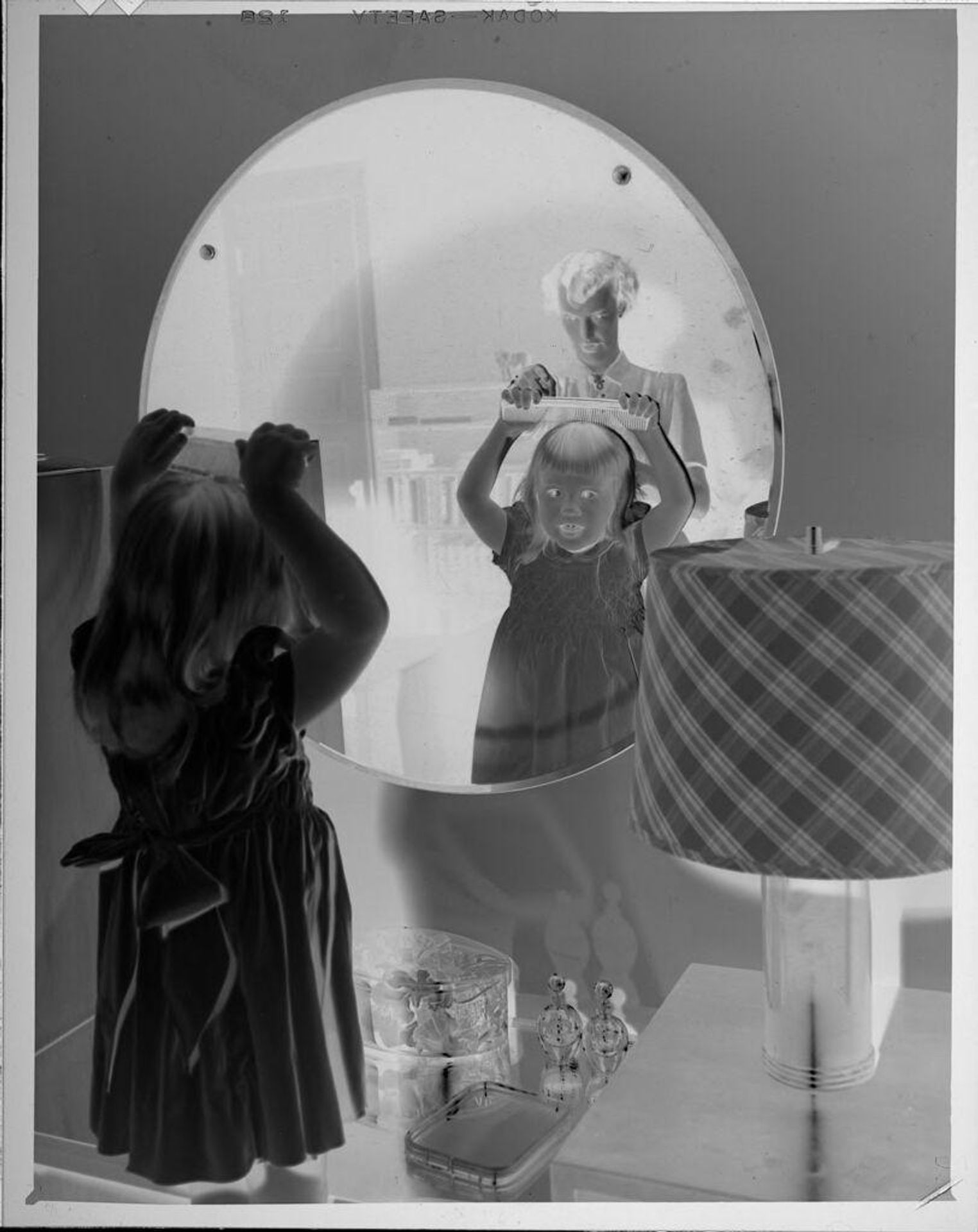 Untitled (girl combing hair in front of mirror) by Lucian and Mary Brown