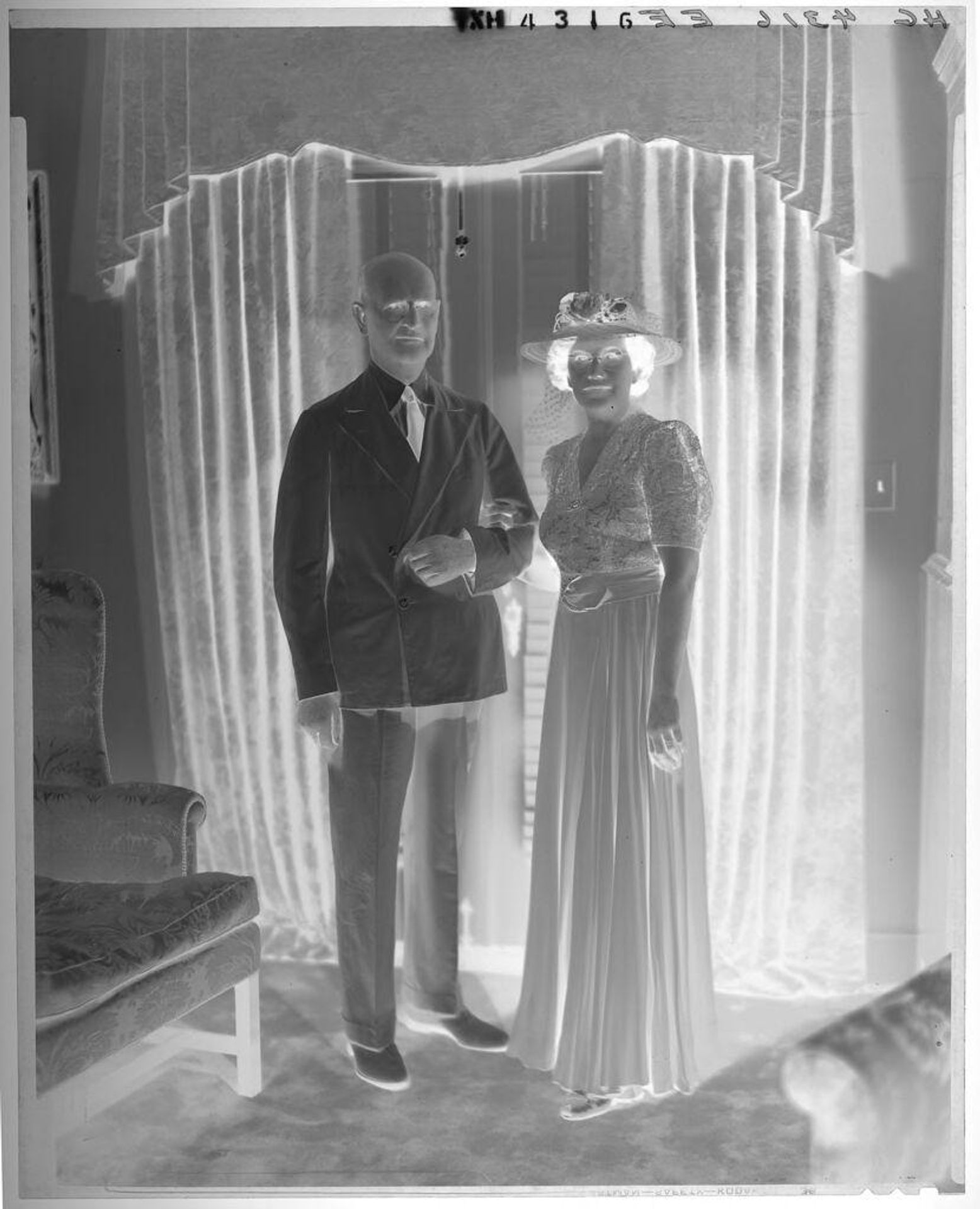 Untitled (portrait of couple standing in living room in front of curtained window) by Paul Gittings
