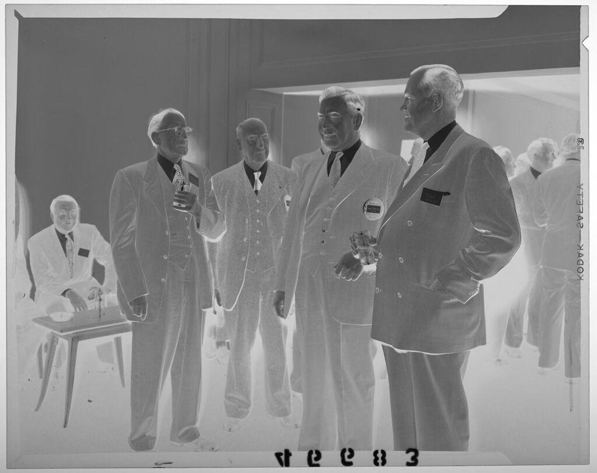 Untitled (four men in suits chatting at shoe company get-together) by Martin Schweig