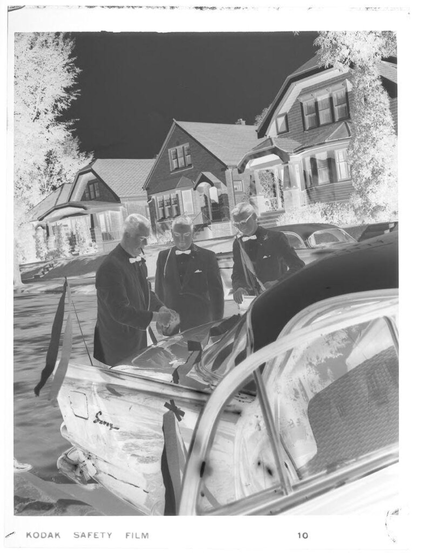 Untitled (three men in bow ties decorating car) by John Deusing