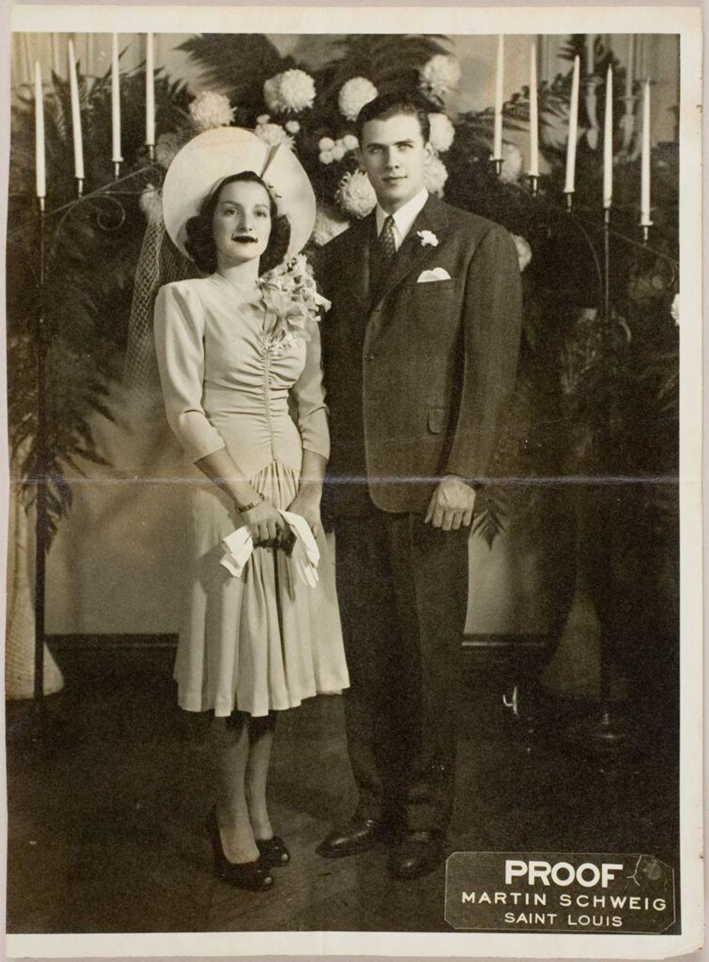 Untitled (young couple posed standing in front of candelabra and flowers) by Martin Schweig