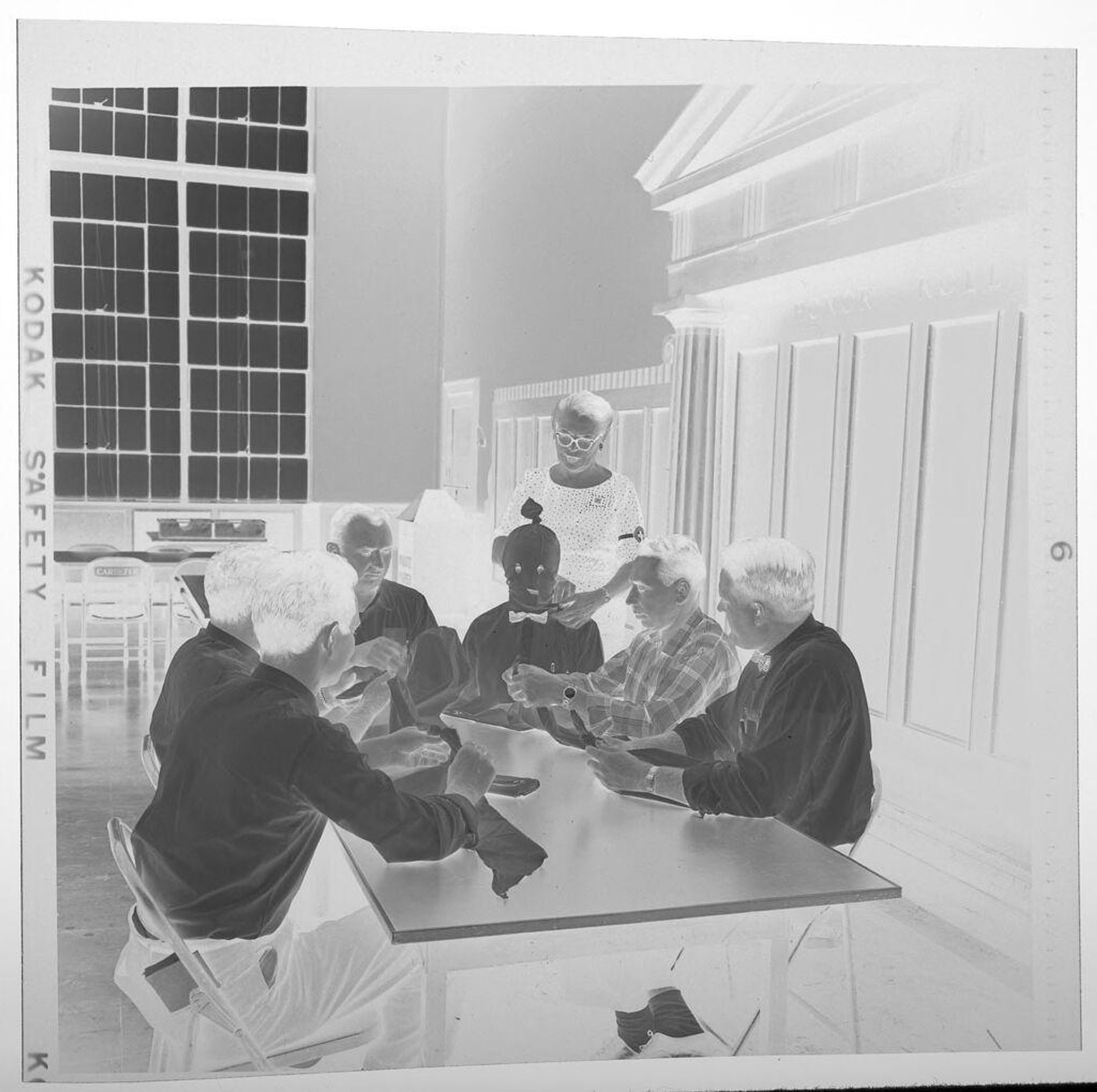 Untitled (people gathered around table learning to tie scarves) by Jack Gould