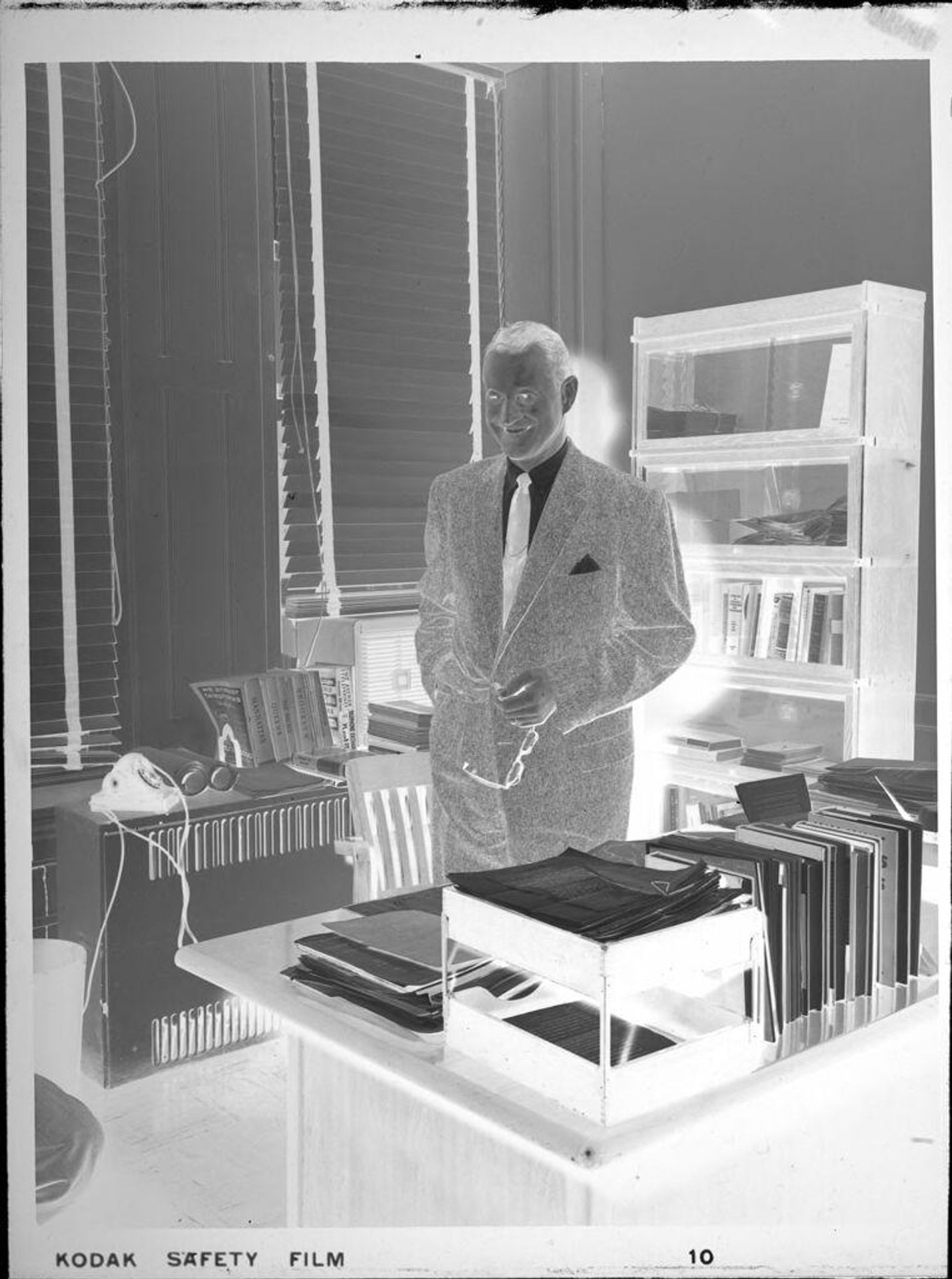 Untitled (man standing behind desk, smiling) by Peter James Studio