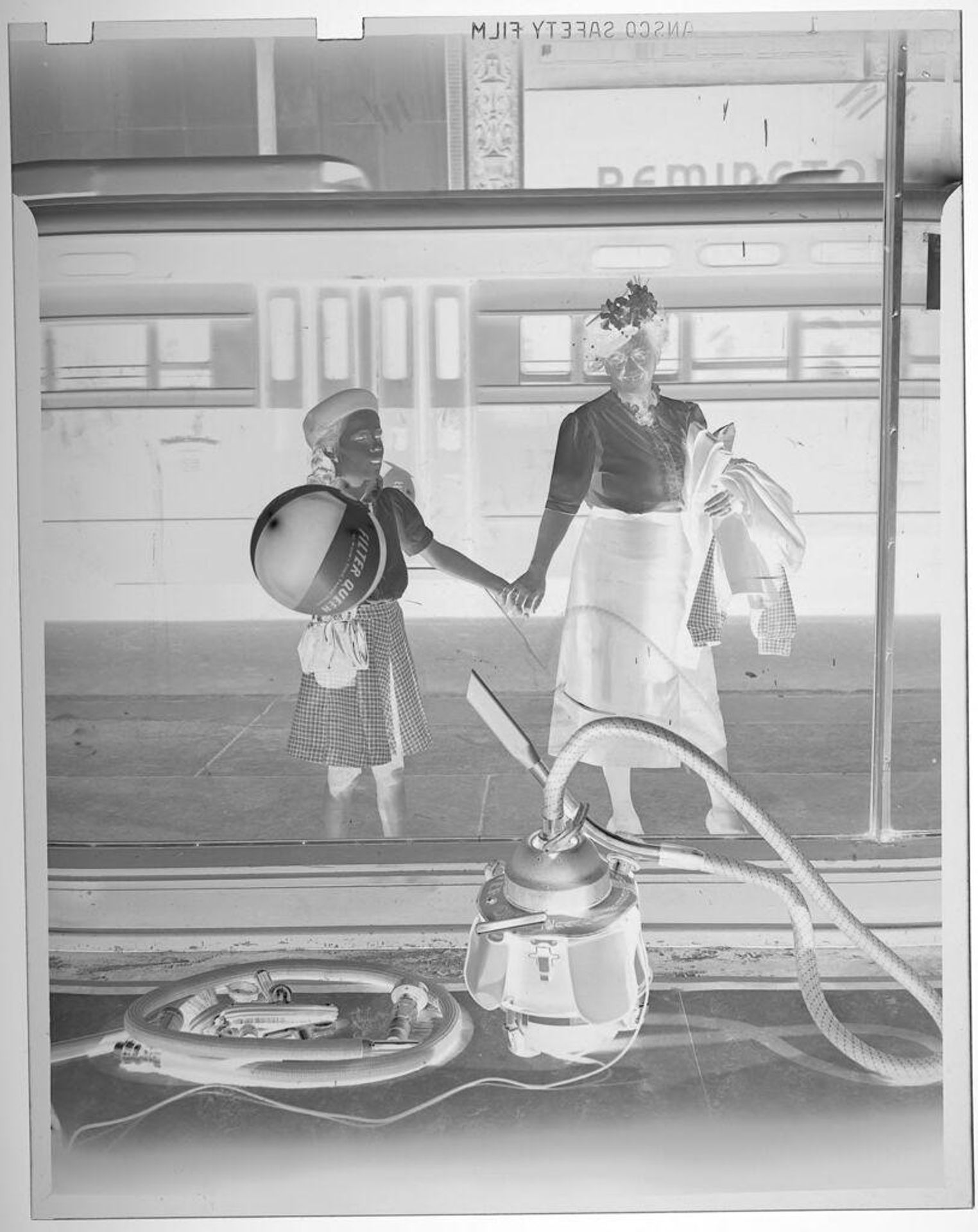Untitled (woman and girl looking into shop window at mysterious vacuum display) by Jack Gould