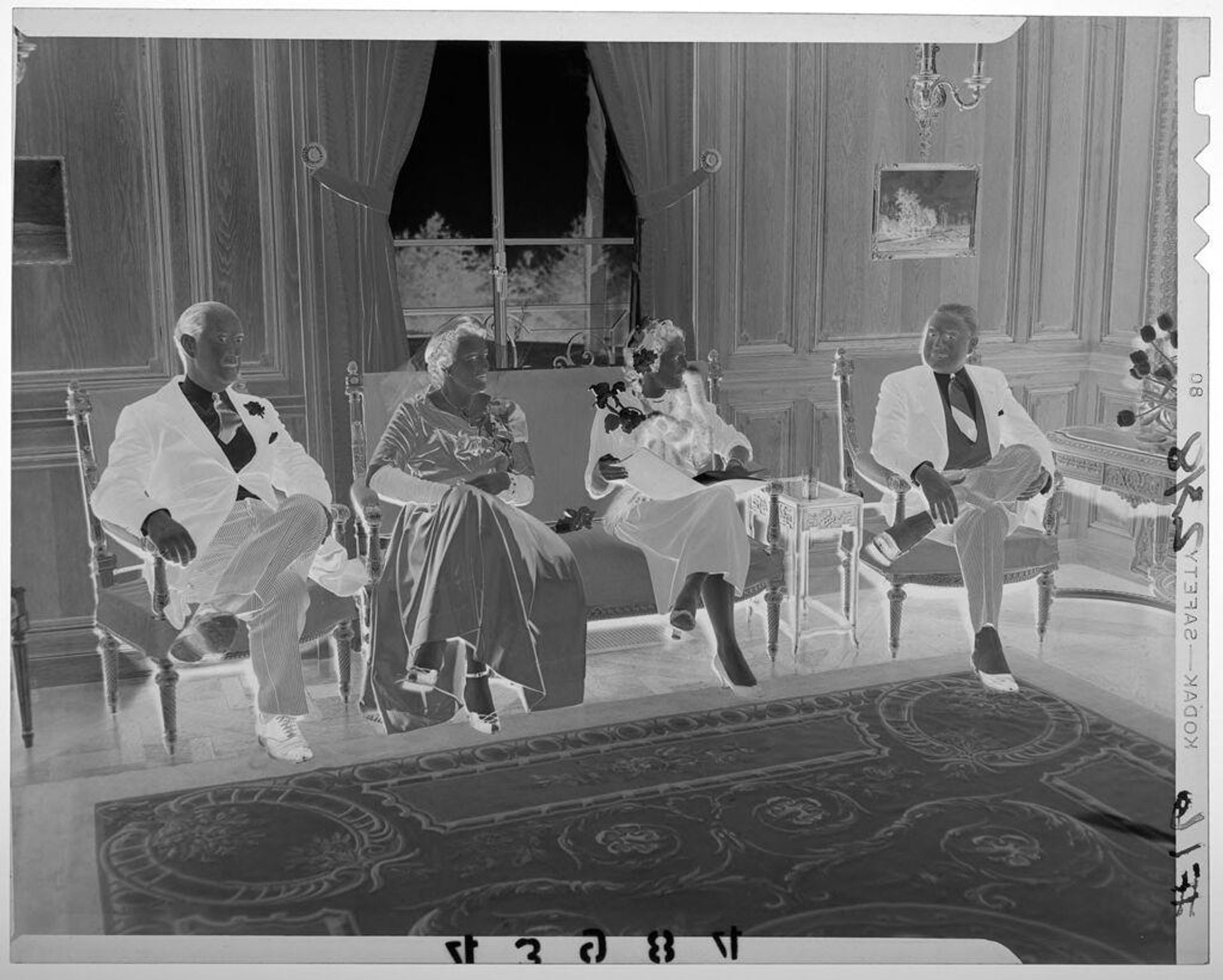Untitled (two men and two women in formal wear sitting and chatting in elegant room) by Martin Schweig