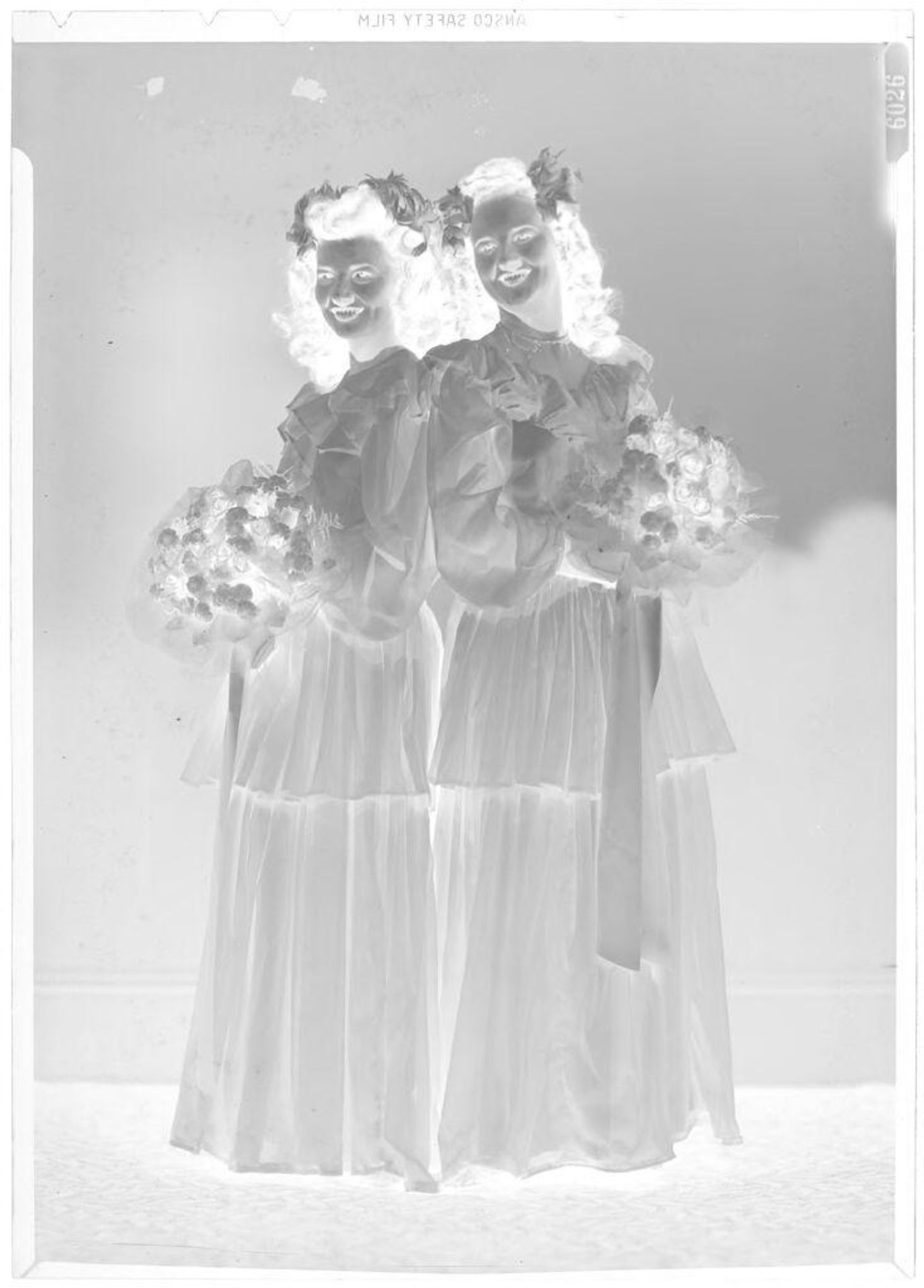Untitled (portrait of two young women with bouquets, bridesmaids) by John Deusing
