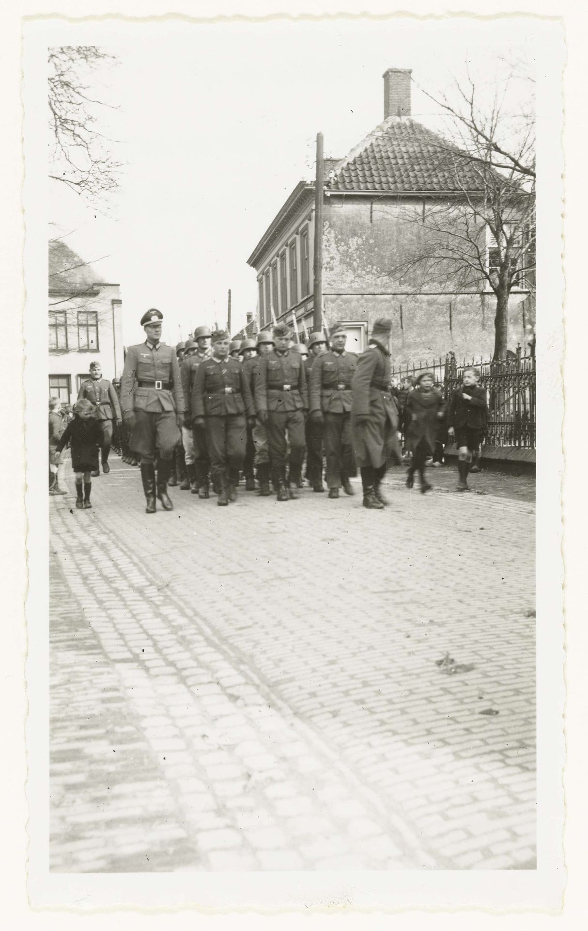 Wehrmacht militairen lopen in een straat by Anonymous