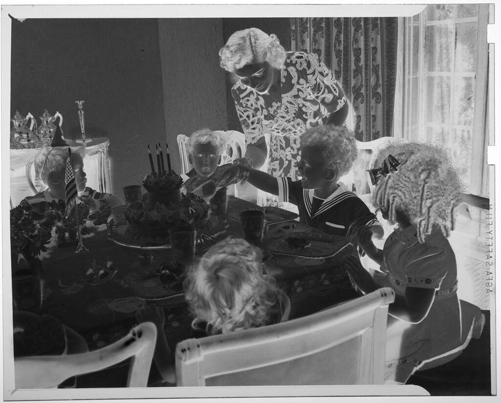 Untitled (young boy cutting cake with assistance of mother at children's birthday party table) by Martin Schweig