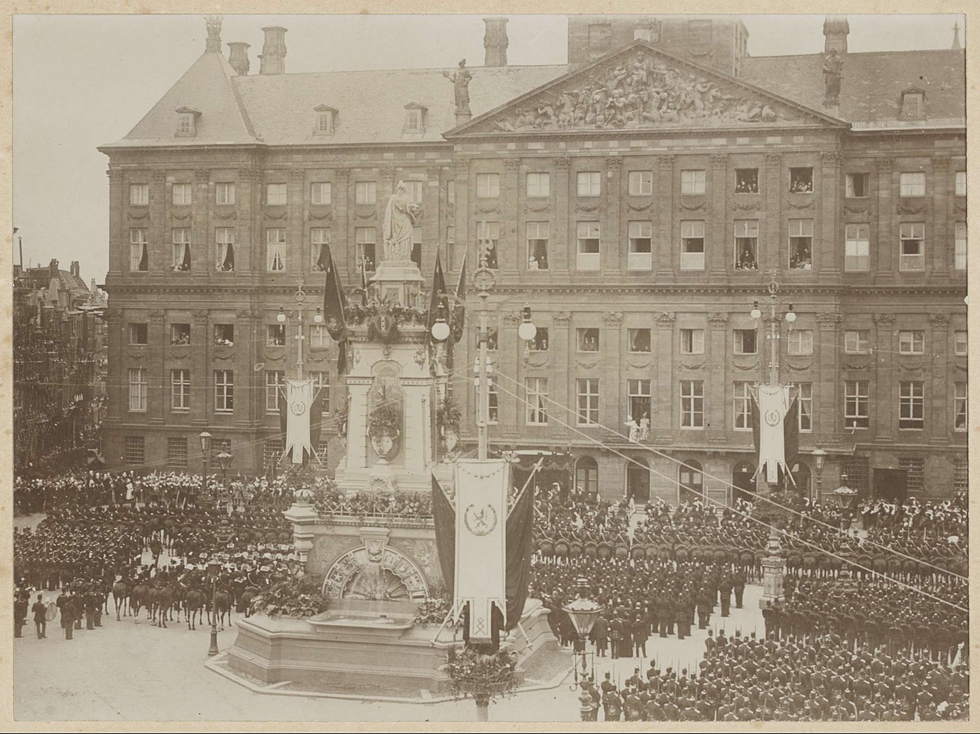 Militair saluut aan de ingehuldigde Koningin Wilhelmina en Koningin-Moeder Emma, beiden staand op het balkon van het Koninklijk Paleis op de Dam by Guy de Coral & Co.