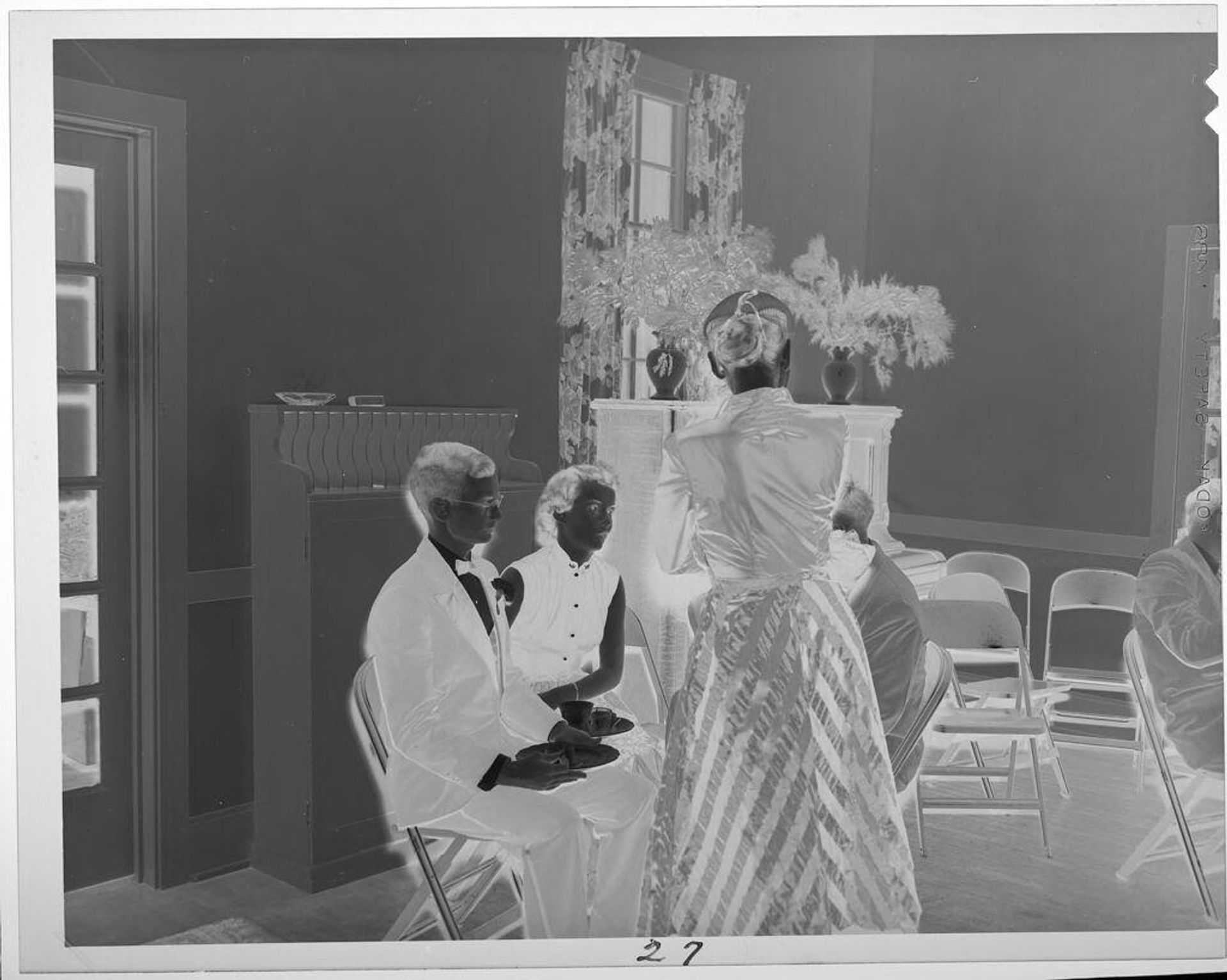 Untitled (people in formal attire on folding chairs) by Lucian and Mary Brown