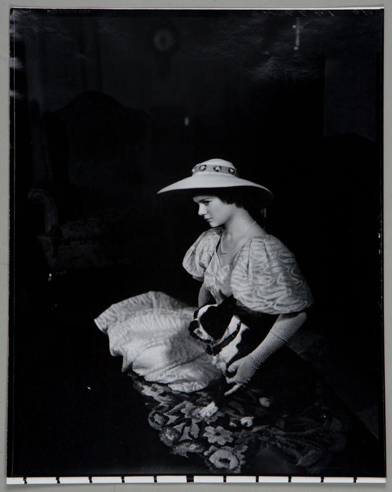 Untitled (woman in hat and white patterned dress seated on rug with dog) by Paul Gittings
