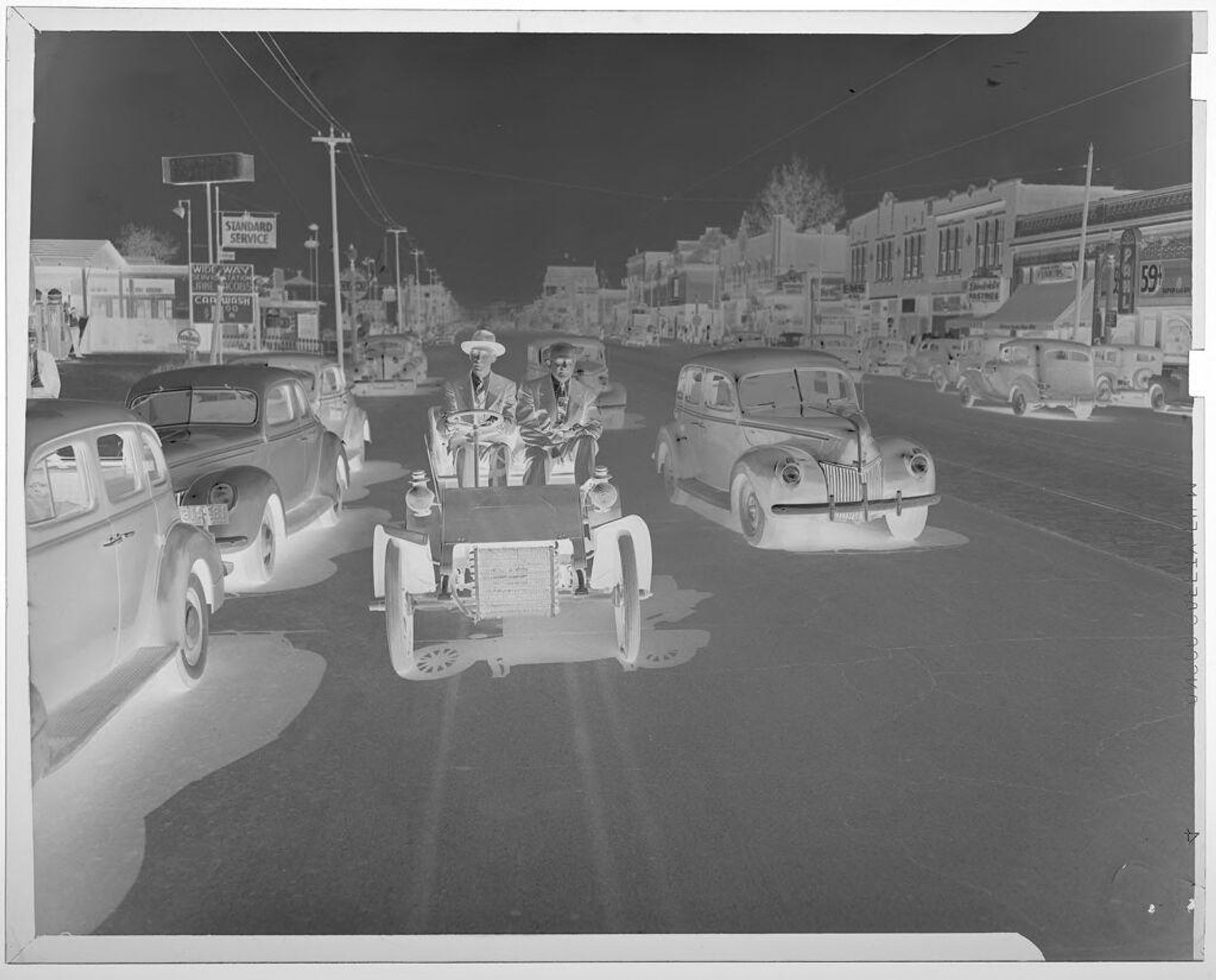 Untitled (men driving old car down city street) by Jack Gould