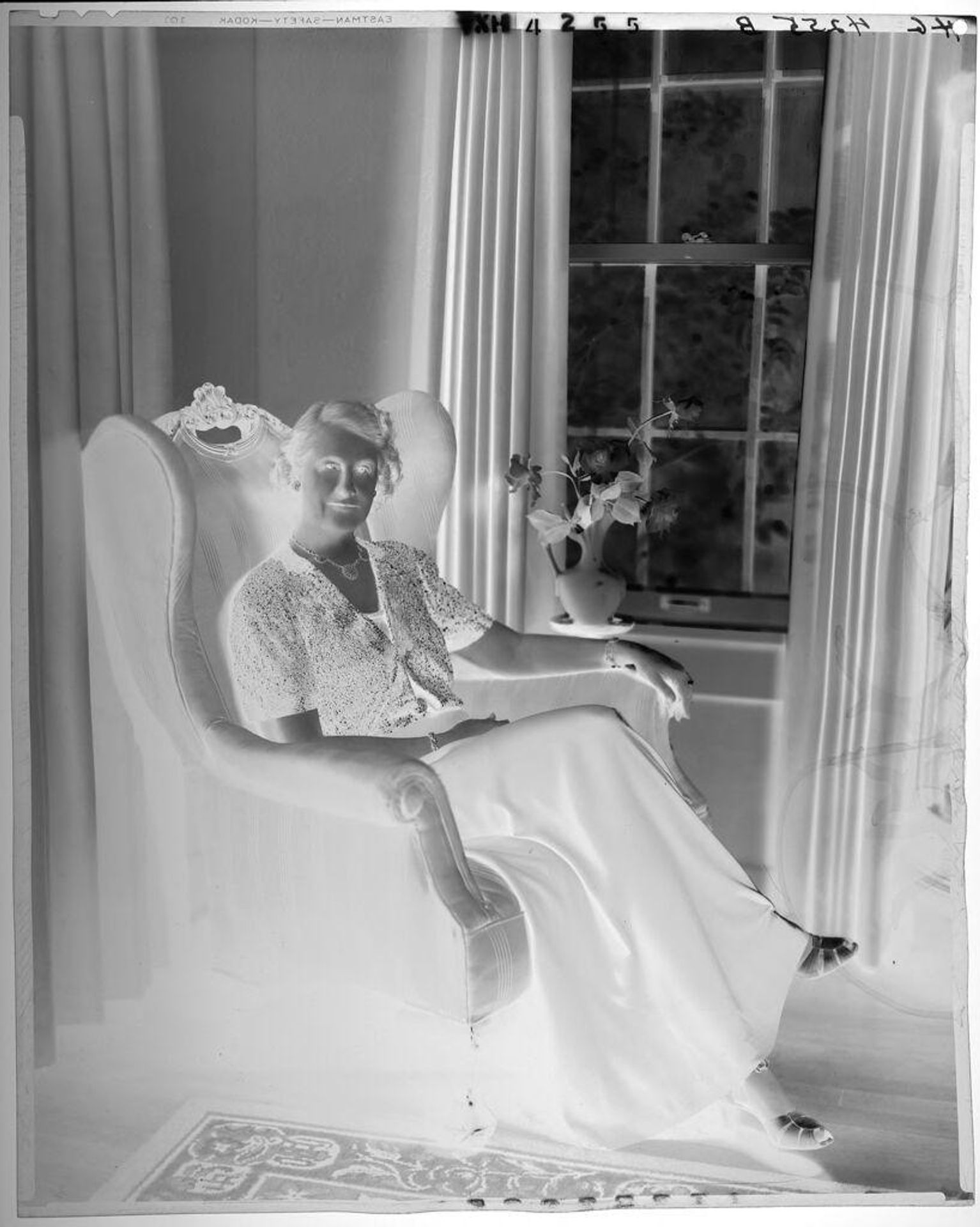 Untitled (woman in beaded jacket and long dress seated in chair by window) by Paul Gittings