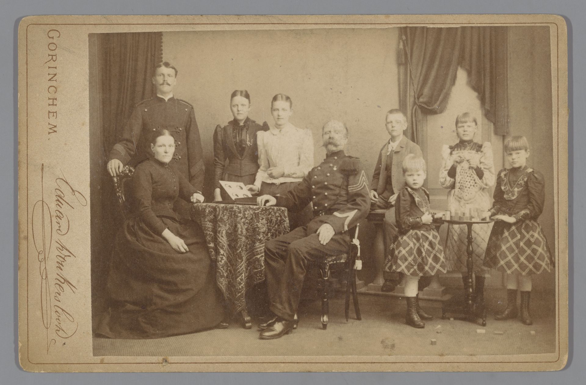 Groepsportret van een familie met een opengeslagen fotoalbum op tafel by Eduard Donkersloot