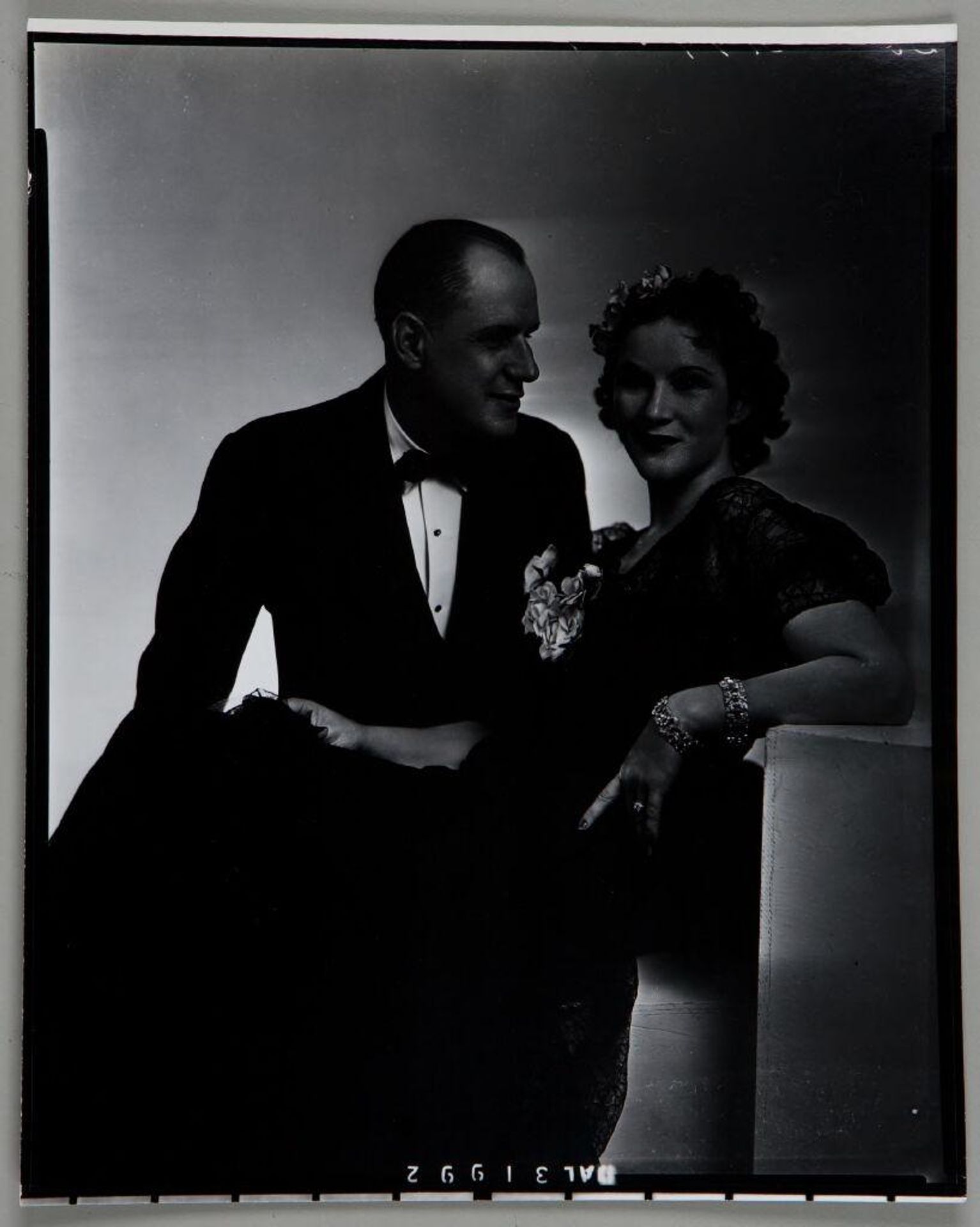 Untitled (studio portrait of man looking at woman who leans back on prop, both in formal attire) by Paul Gittings