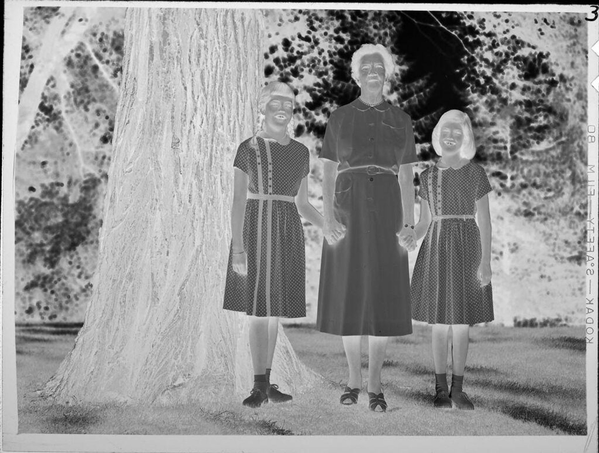 Untitled (woman and two girls in matching dresses standing outside) by Lucian and Mary Brown