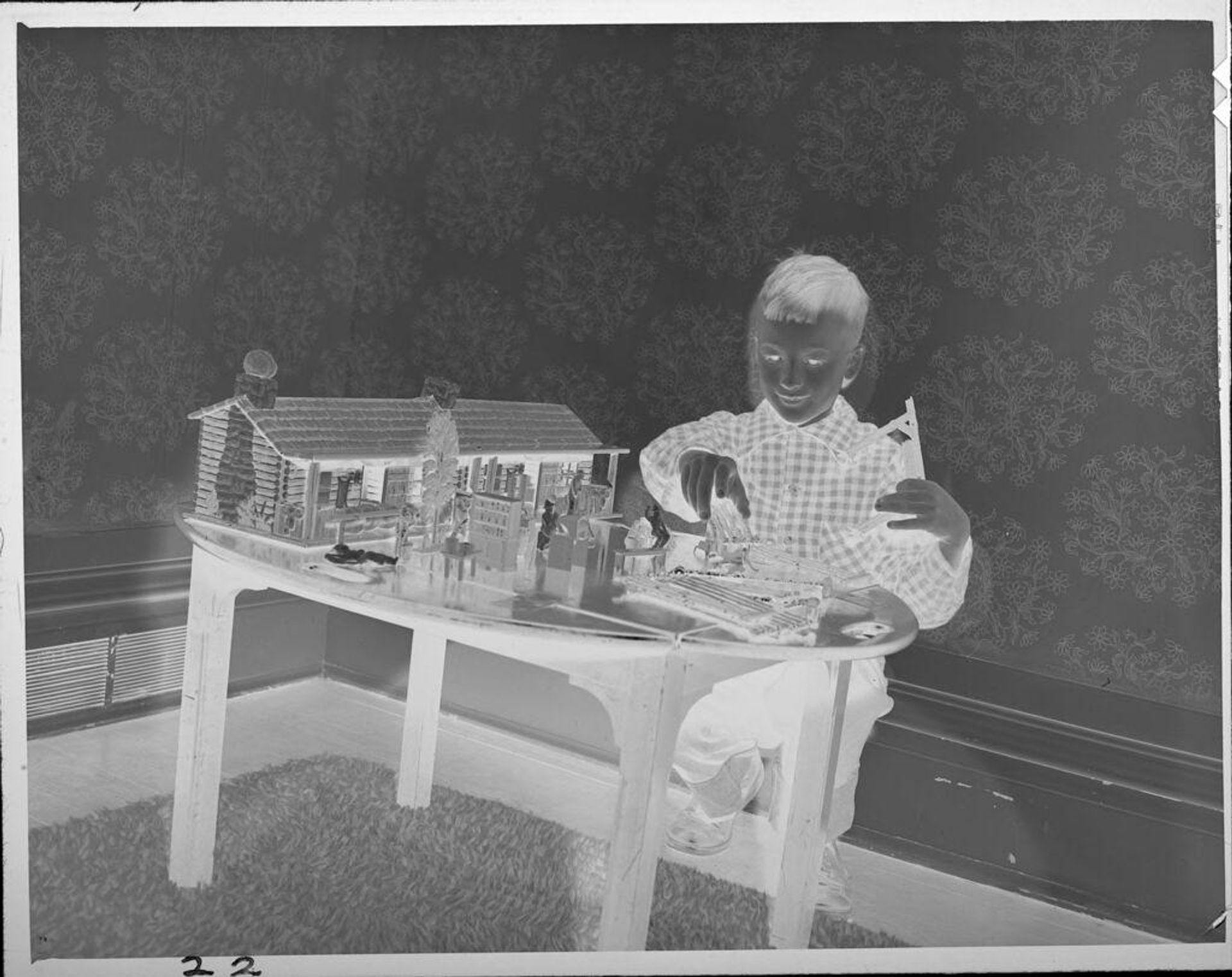 Untitled (boy playing with model house) by Lucian and Mary Brown