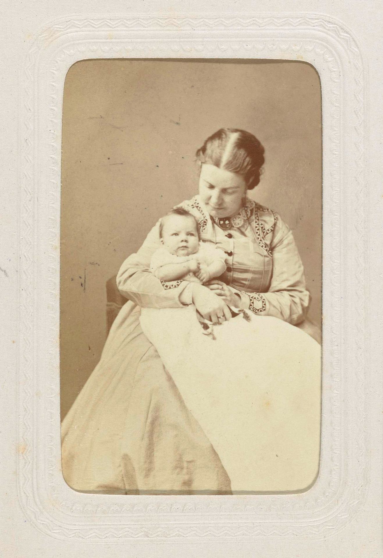 Studioportret van een vrouw met een baby in witte jurk op schoot by Wegner & Mottu