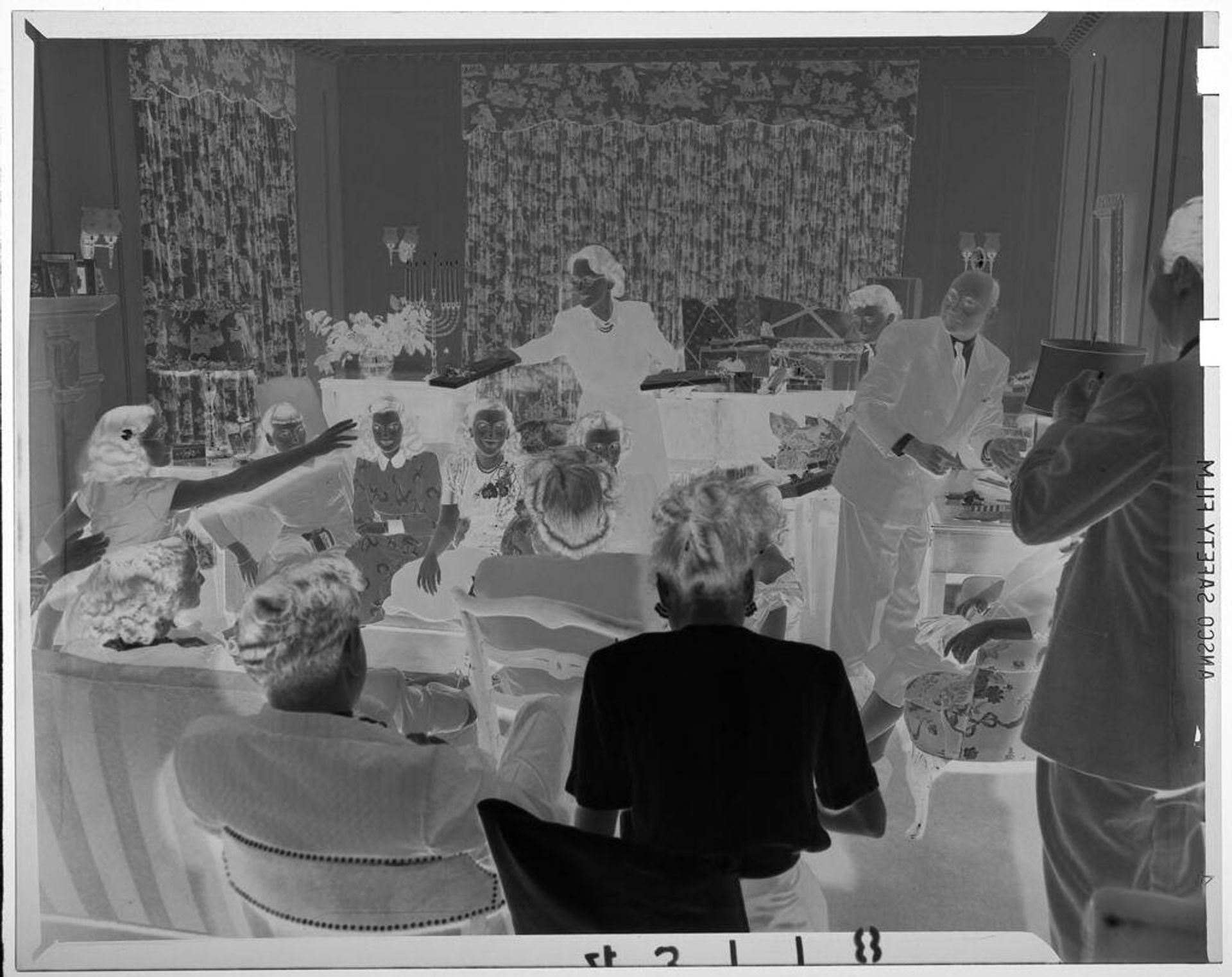 Untitled (view of living room with woman passing out holiday gifts and adults sitting on couches) by Martin Schweig