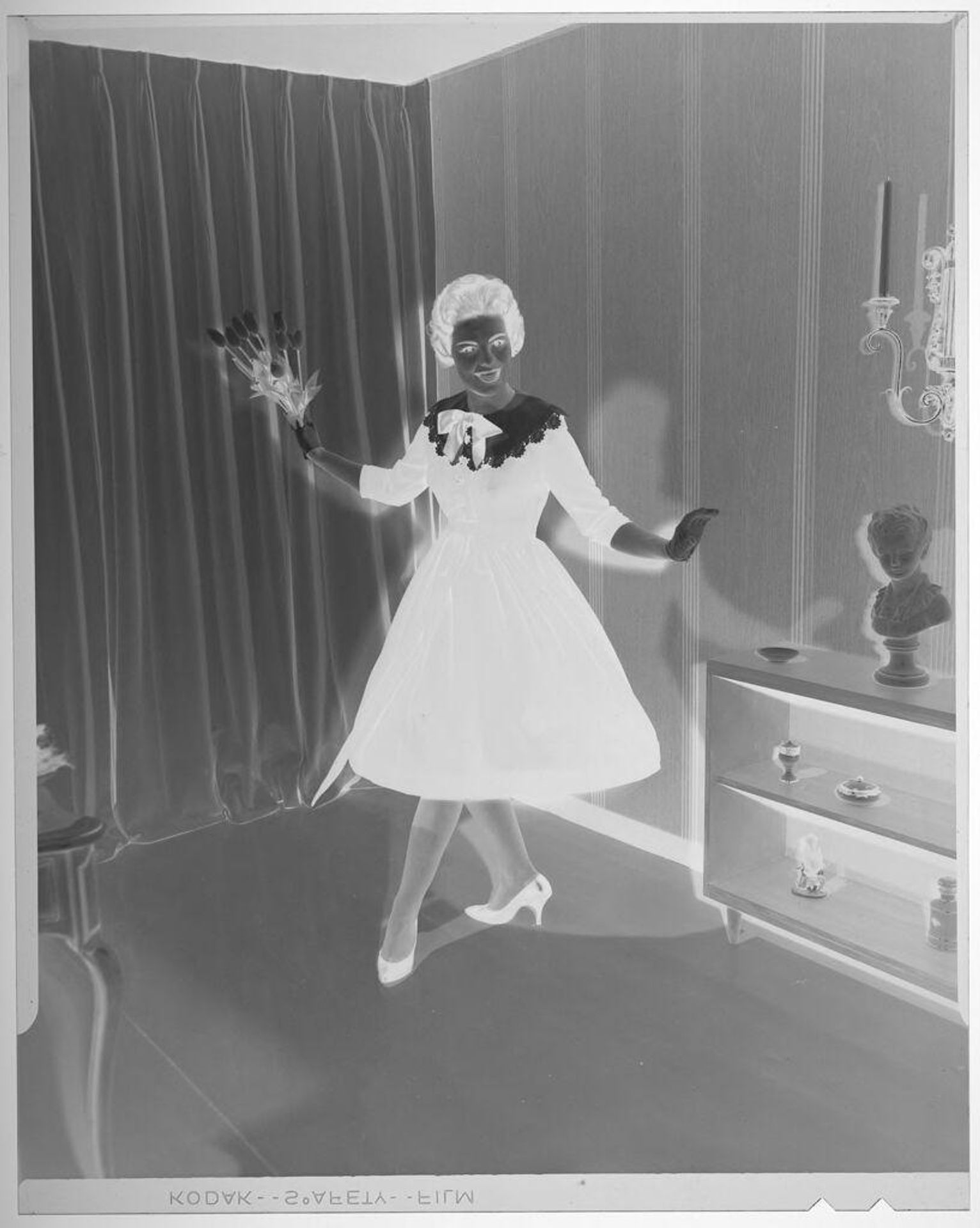 Untitled (fashion portrait of woman in dress with large bow holding tulips in stylized pose) by Martin Schweig