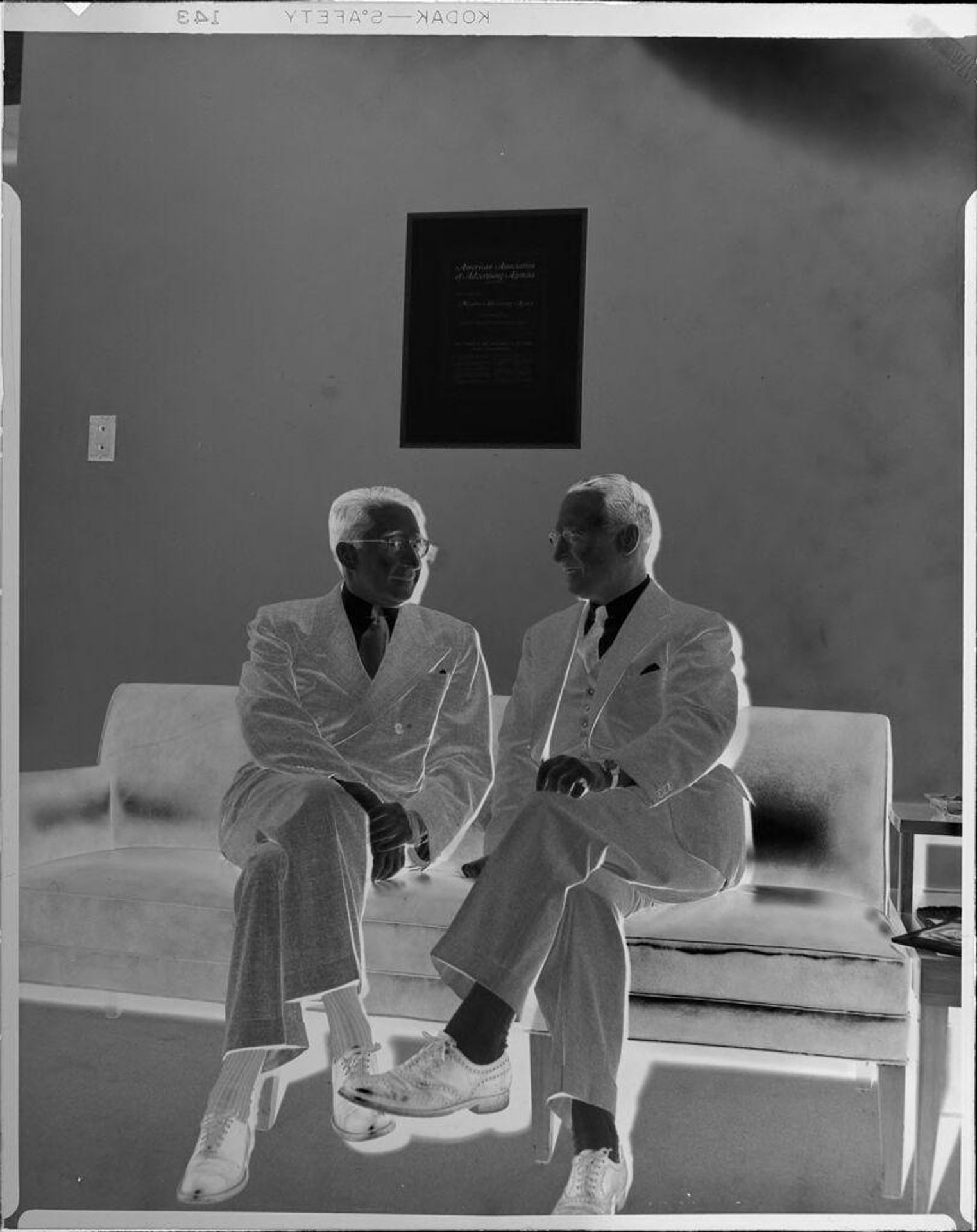 Untitled (two men sitting on couch) by Peter James Studio