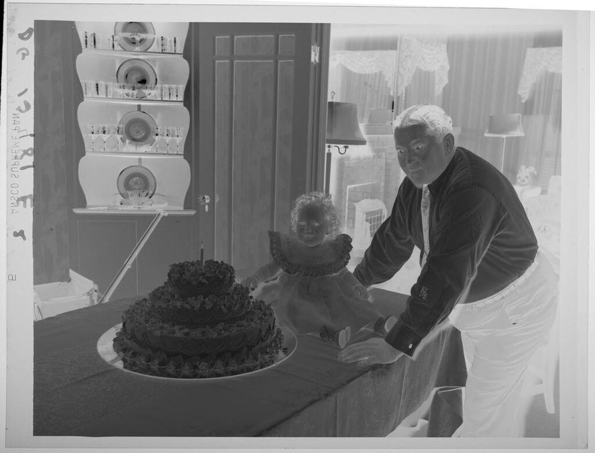 Untitled (little girl seated on table next to first birthday cake, father leaning next to her) by Paul Gittings