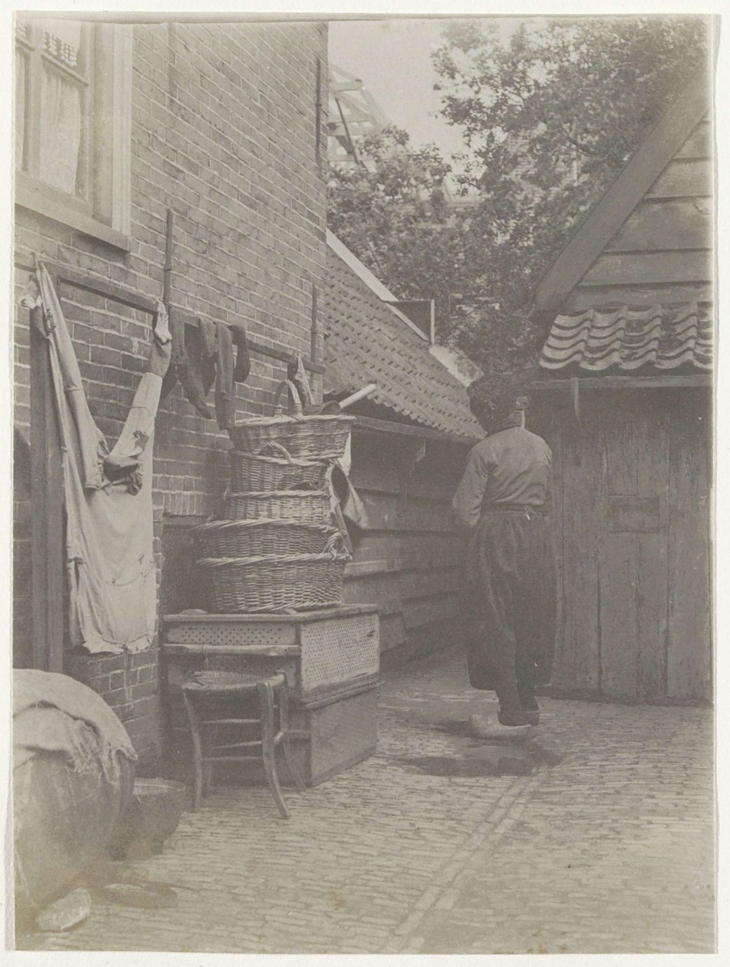 Man in klederdracht staand naast stapels korven, vermoedelijk in Volendam by G. Hidderley