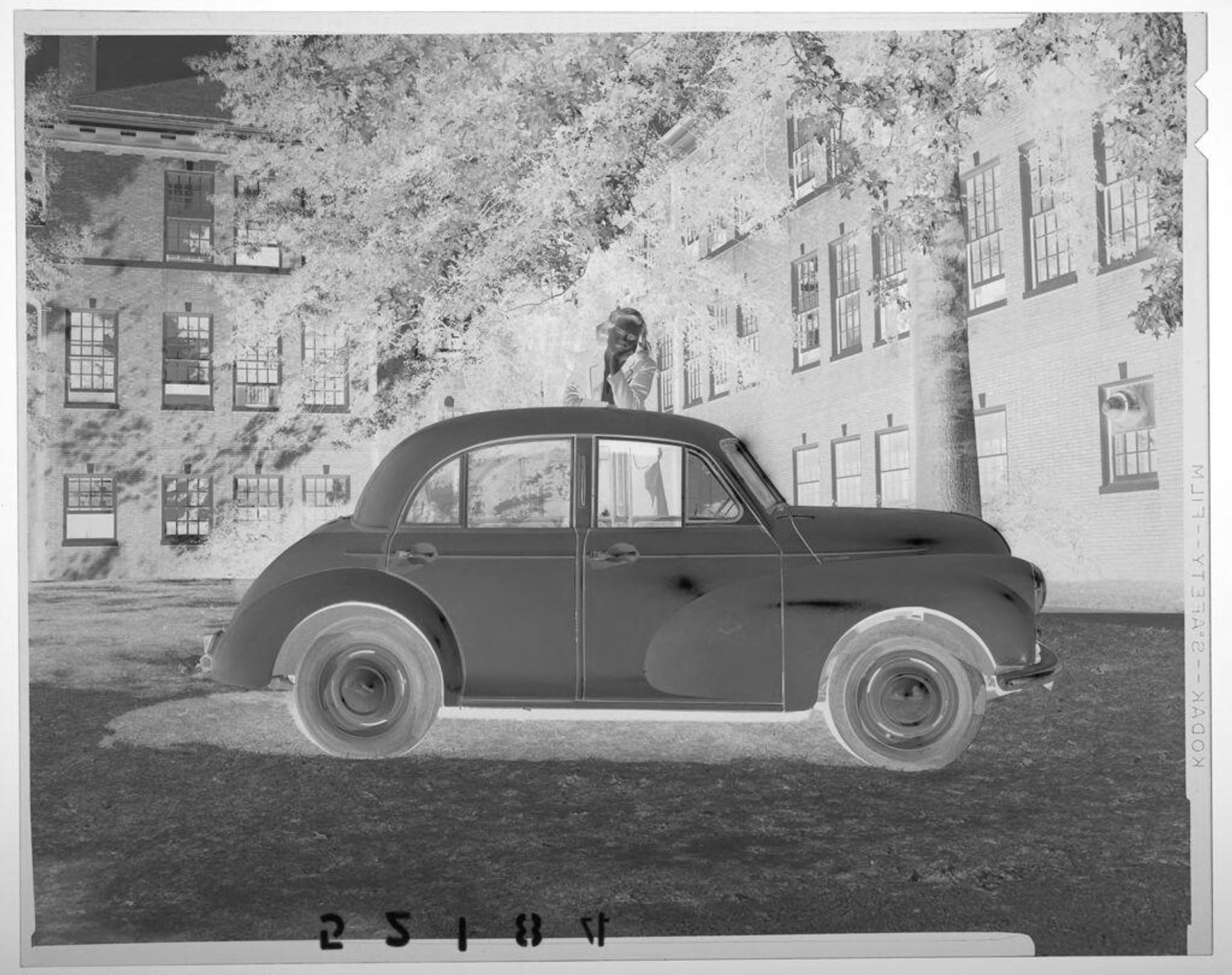 Untitled (woman posed leaning on top of car in school yard) by Martin Schweig