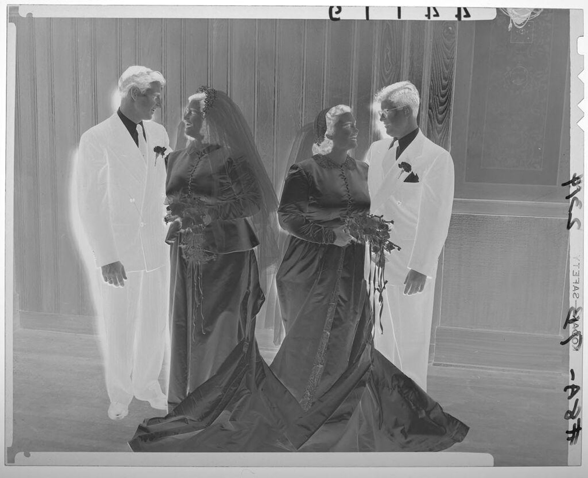 Untitled (two bride and groom couples smiling at each other in front of wood wall) by Martin Schweig