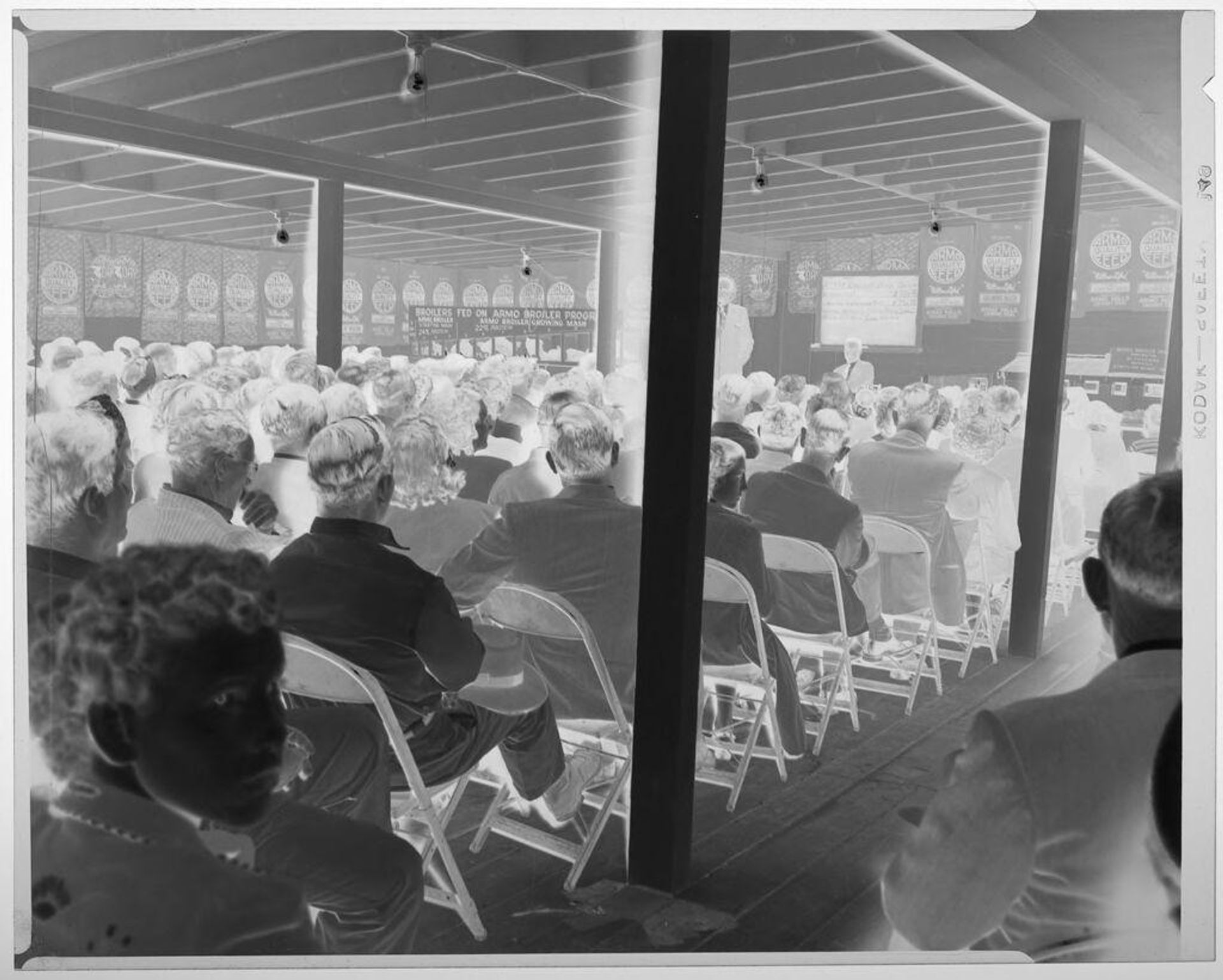 Untitled (audience listening to speaker at Armo Mills Poultry Meeting) by Harry Annas