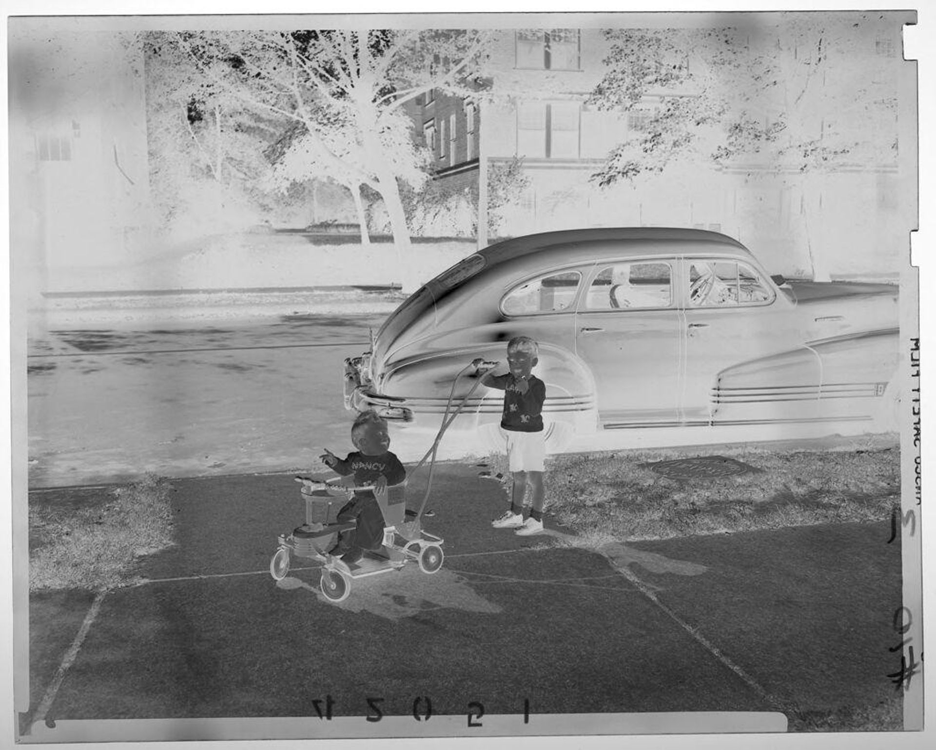 Untitled (young boy pushing baby girl in stroller on residential block) by Martin Schweig