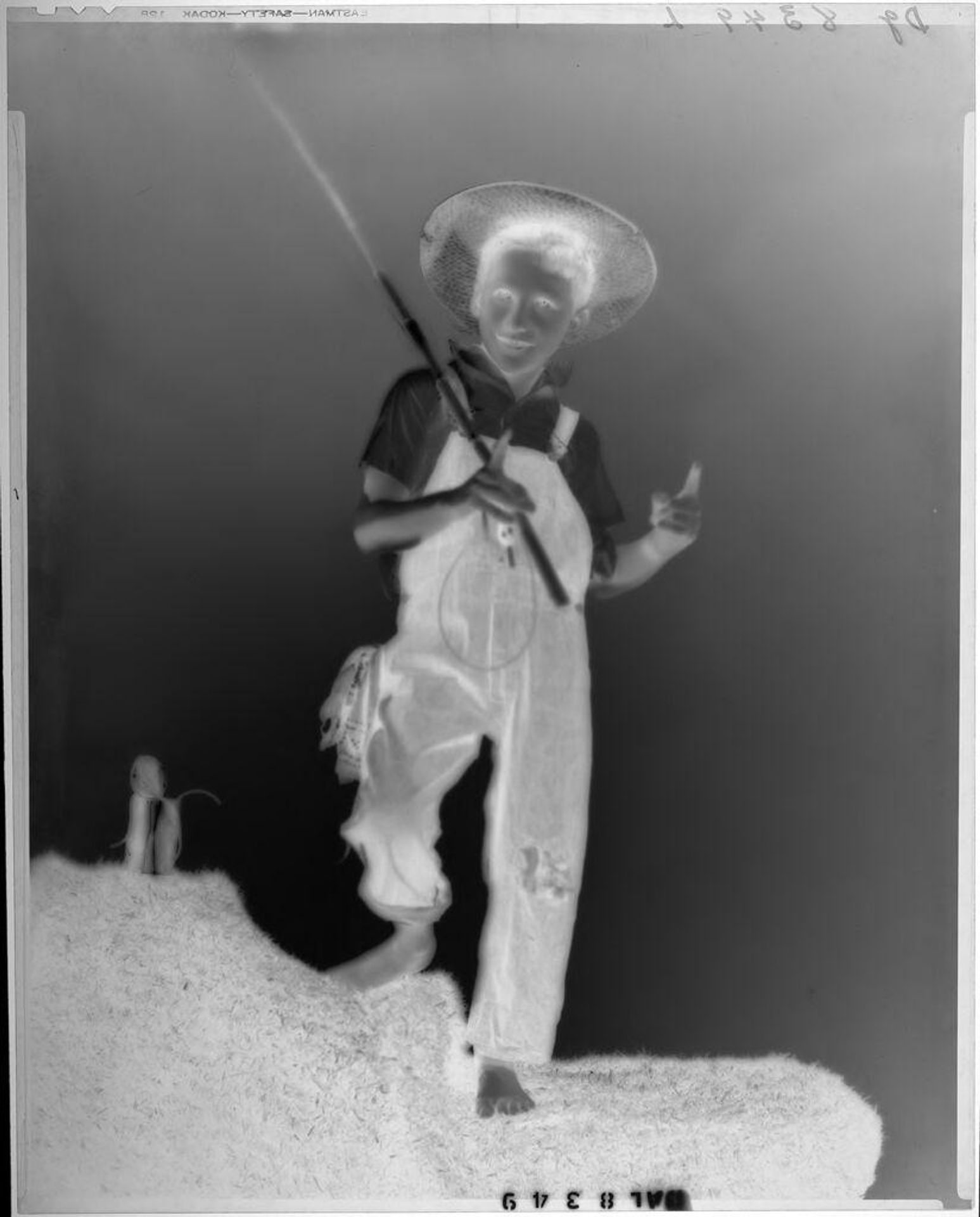 Untitled (young boy dressed as fisherman with pole indicating size of fish caught) by Paul Gittings