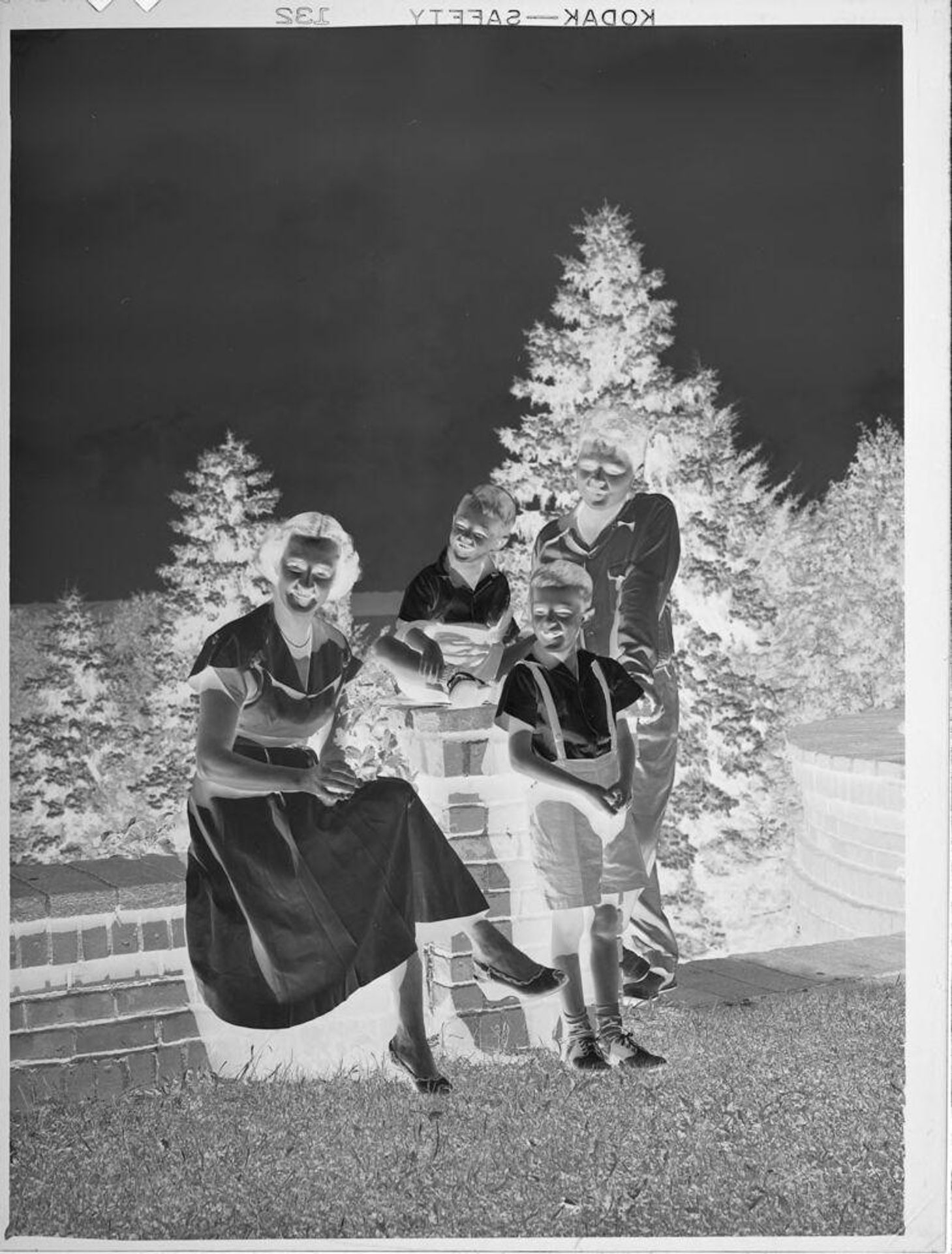 Untitled (woman and three boys on brick wall outside) by Lucian and Mary Brown