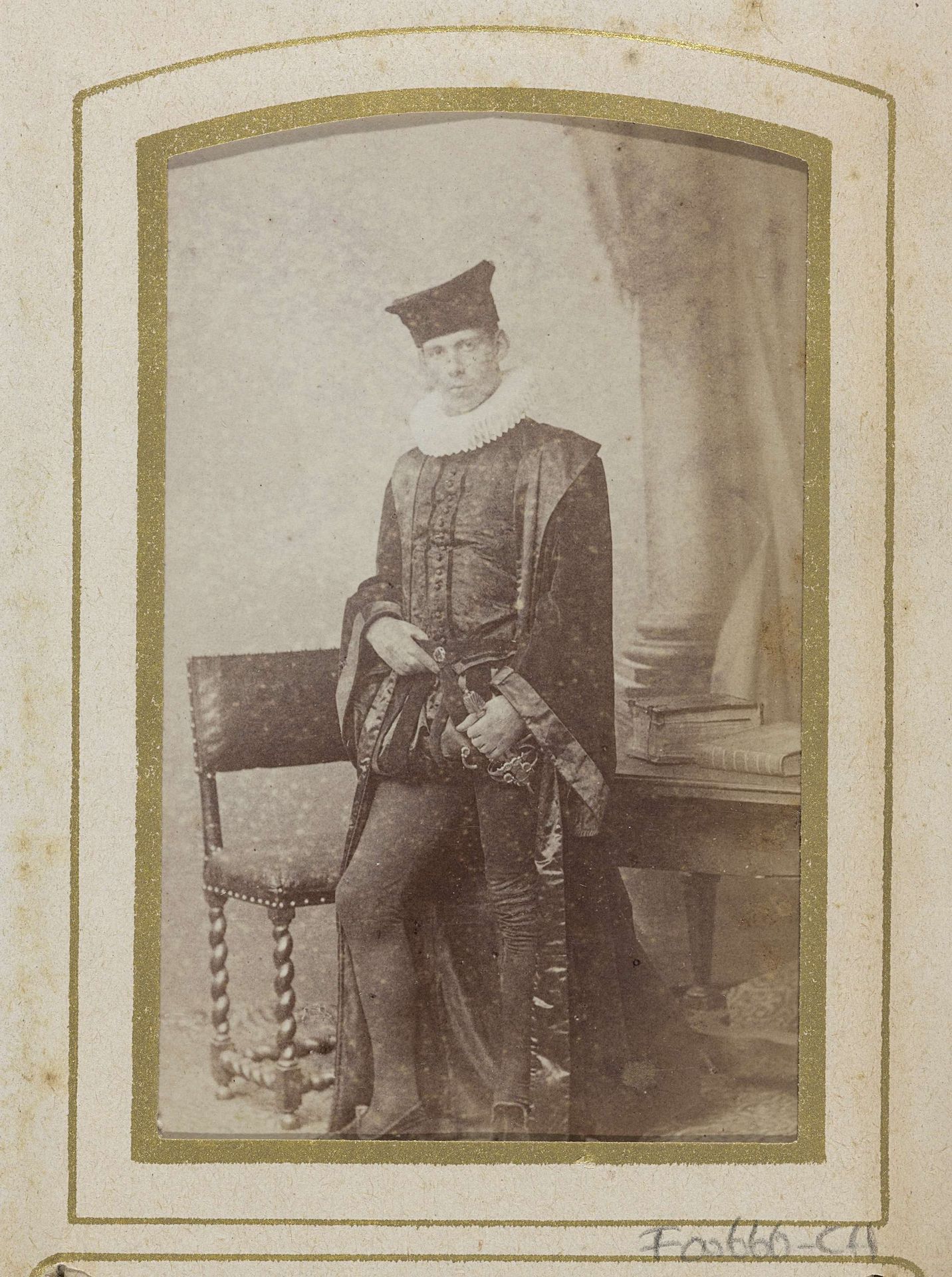 Portret van een jonge man in kostuum bij een stoel en een tafel met boeken, aangeduid als J.W. Huijsinga by Jan Goedeljee